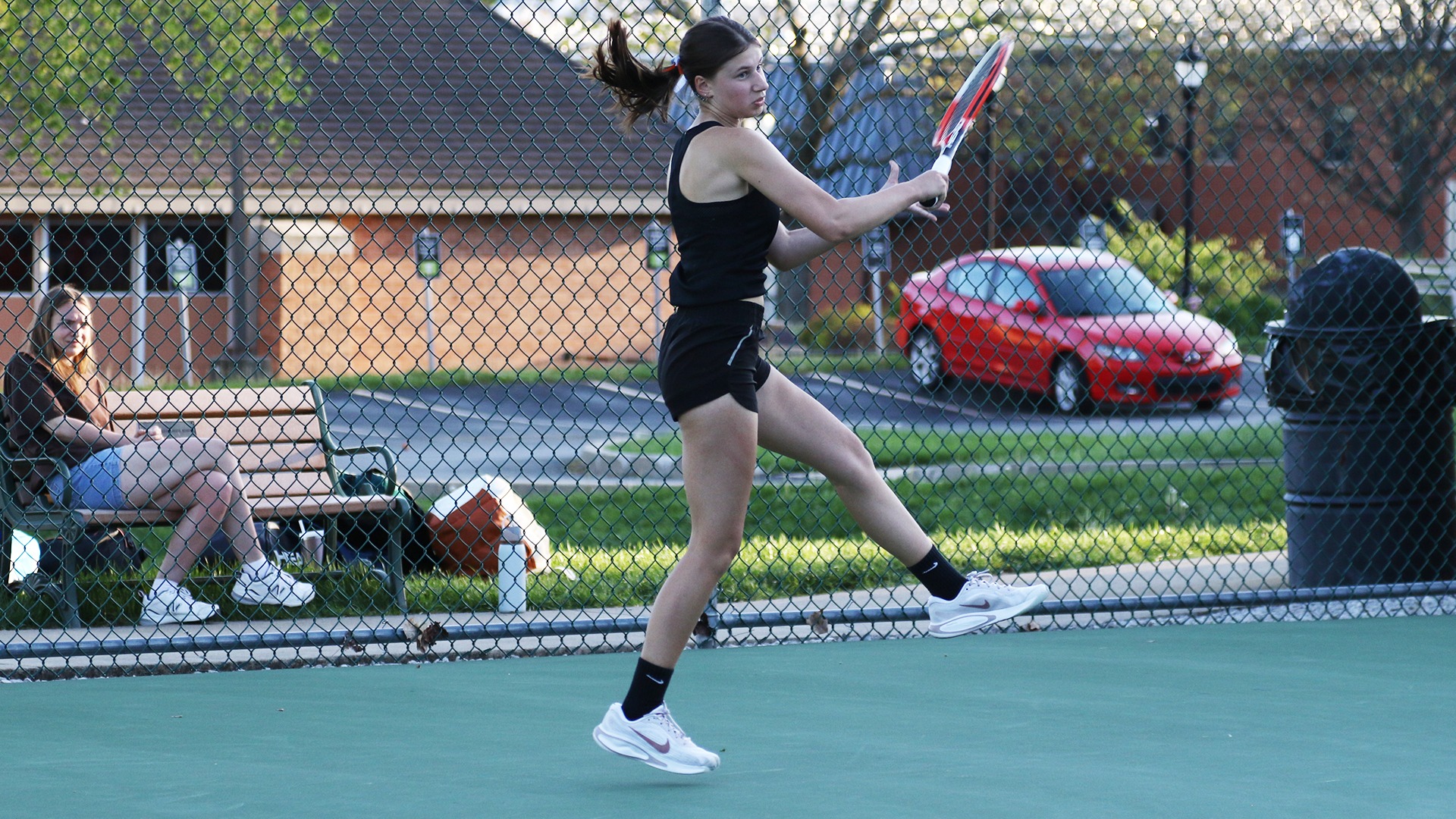 Emily Kowalke in black uniform hitting ball