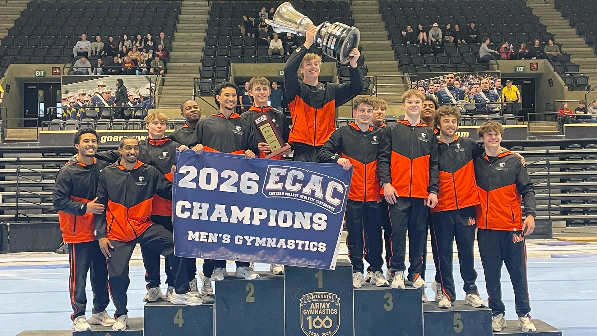 Team picture on podium holding ECAC Champ trophy and banner