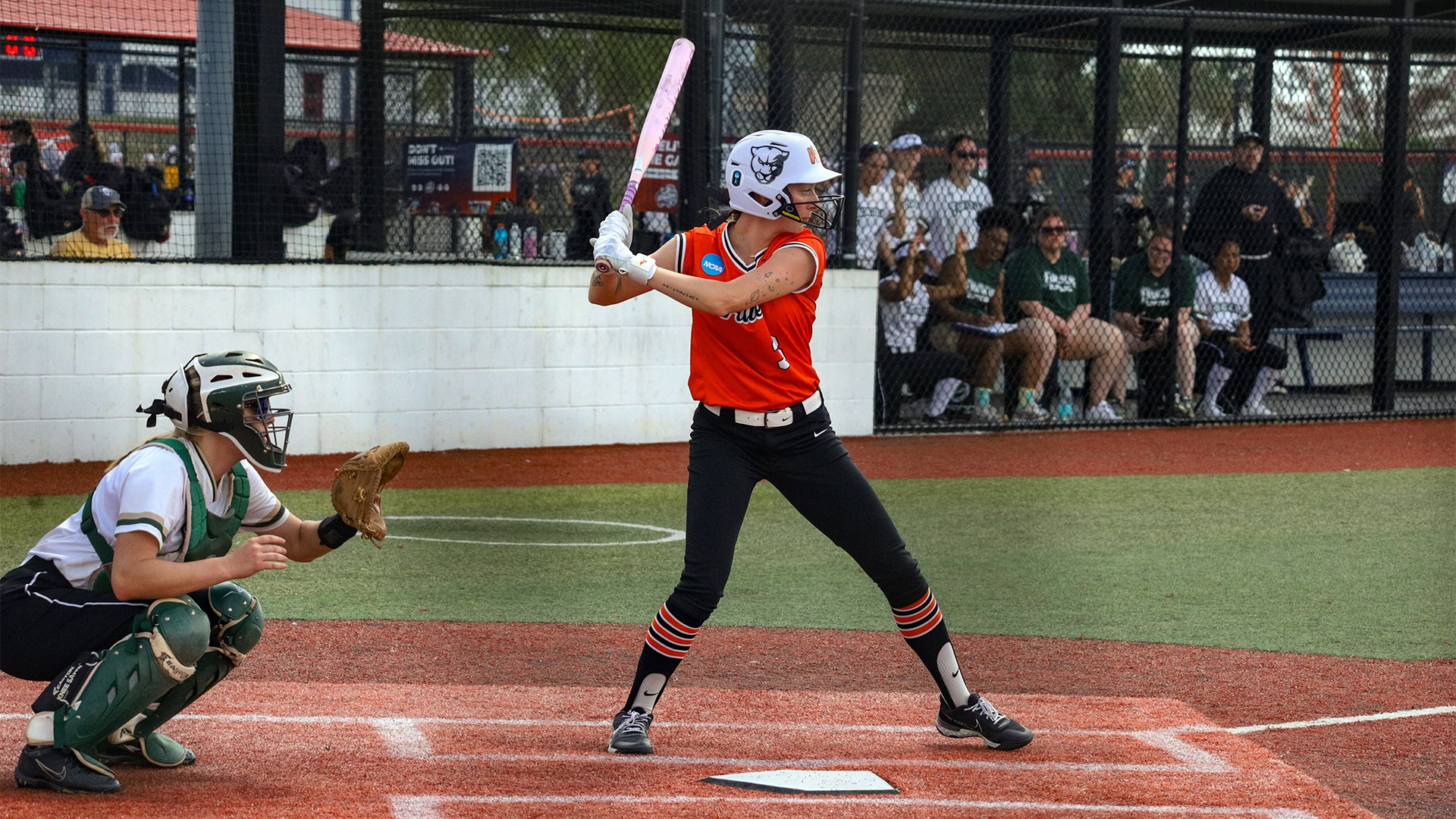 Emma Longcor in orange jersey, in batting stance at the plate