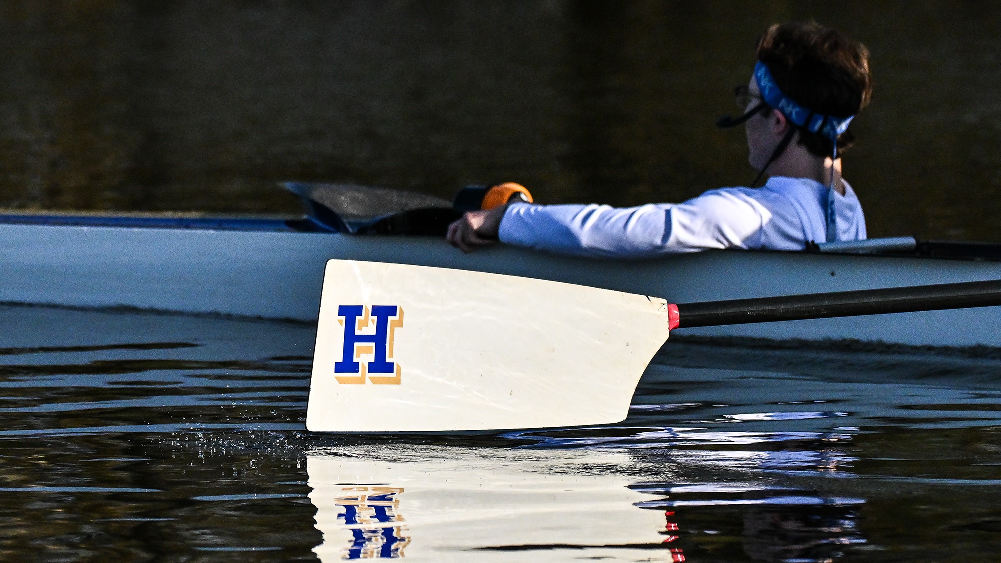 An oar above the water and a coxswain in a boat during rowing practice on the Erie Canal in April 2025