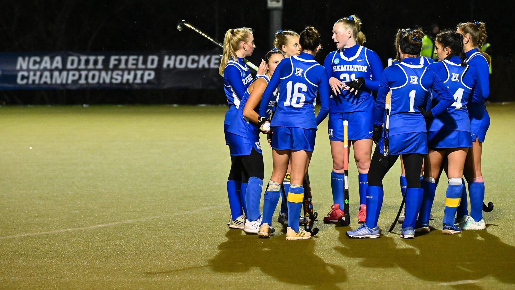 Field Hockey huddles near midfield with the NCAA championship banner in the background at Goodfriend Field