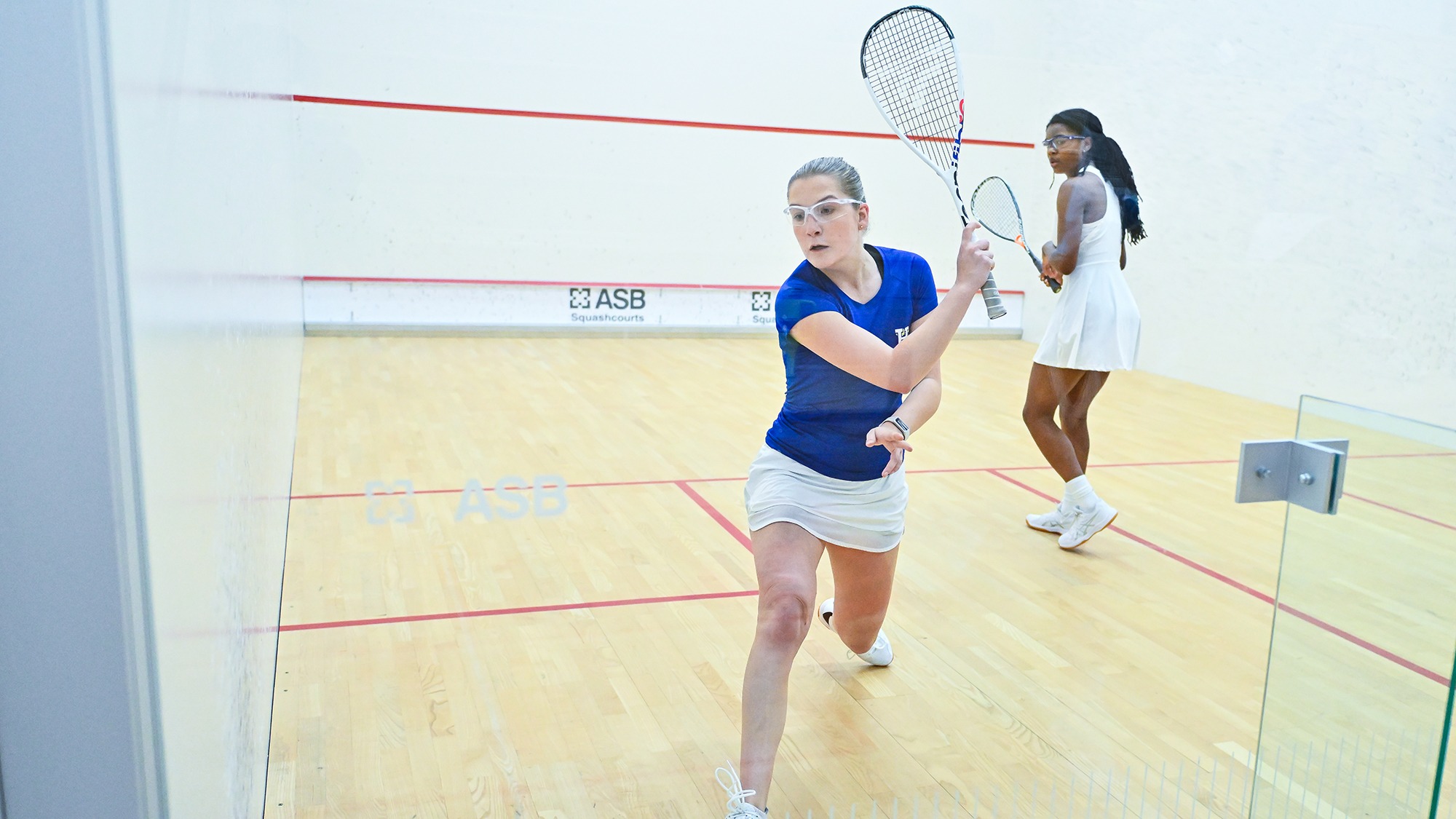 Poppy Huffman hits a backhand shot out of the back corner of the squash court against Denison in December 2025