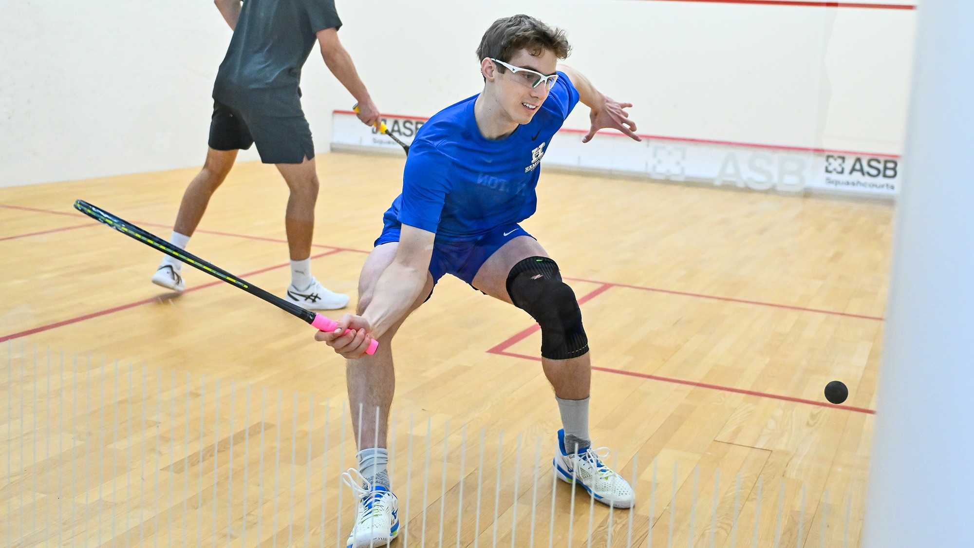 Joseph Applebaum reaches with his racket for the ball close to the wall in a squash match against Denison