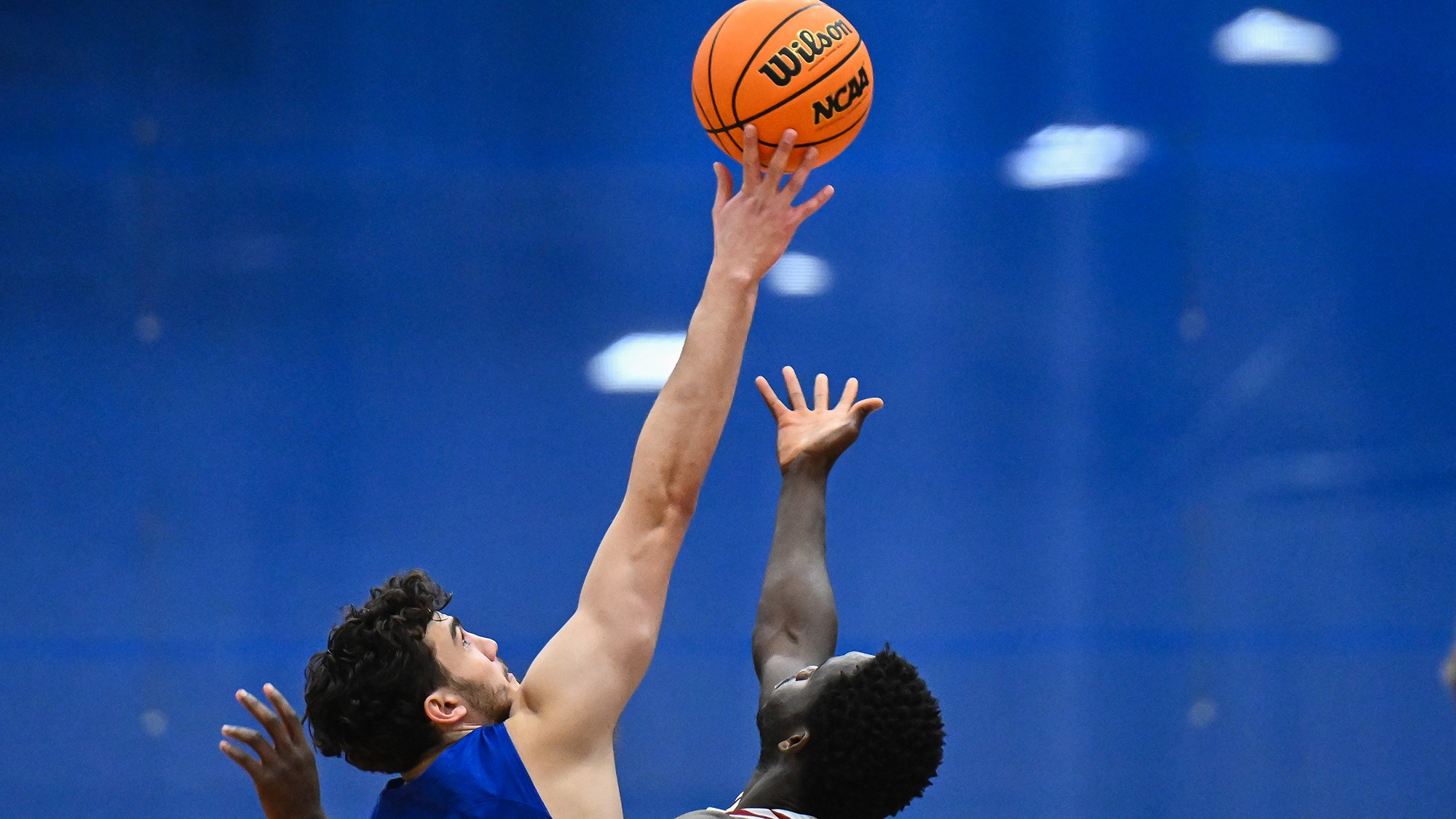 Men's basketball player Garret Keyhani '26 taps the jump ball against Bates