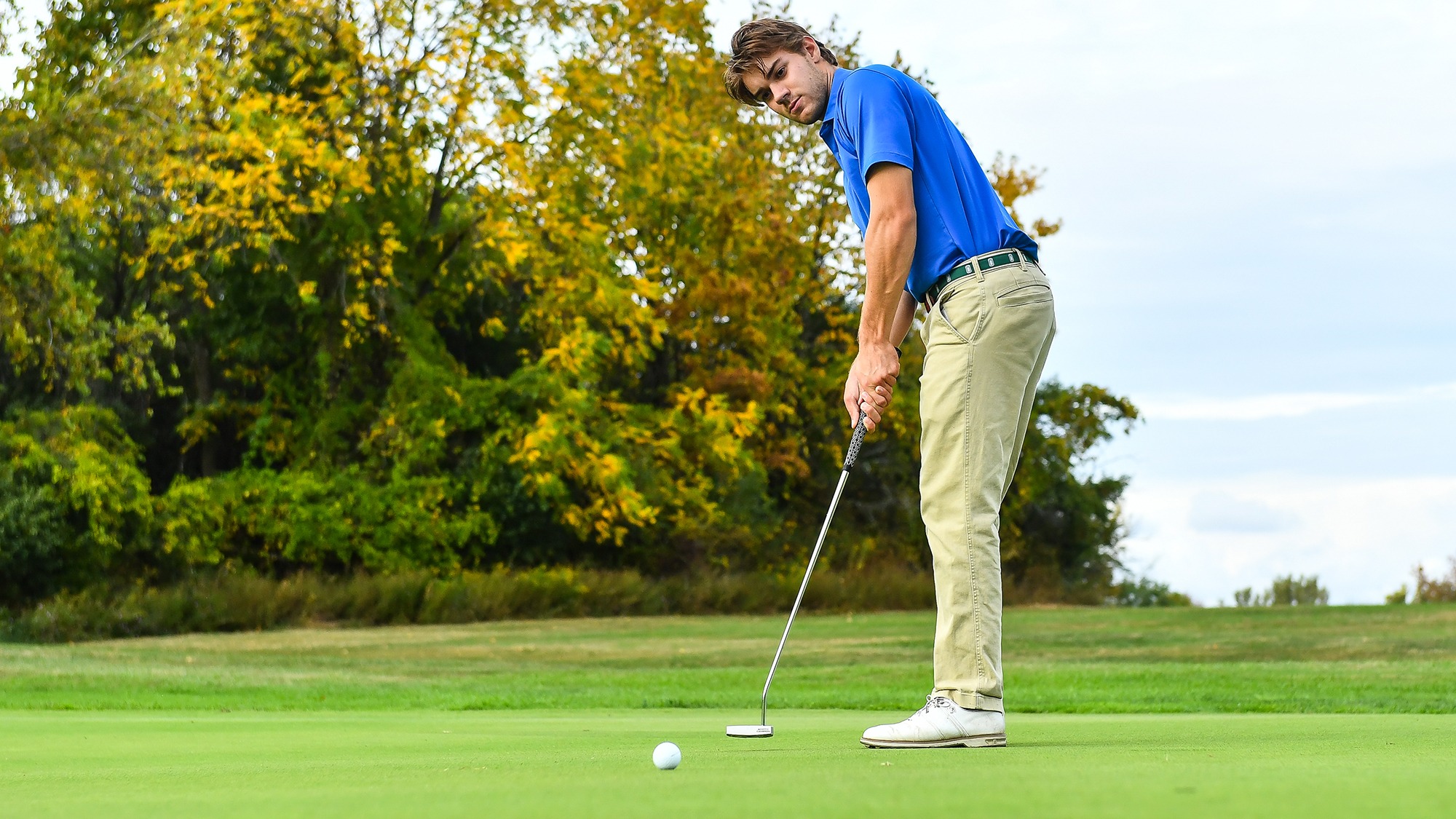 Gunnar Moore putts the ball on the practice green during men's golf practice