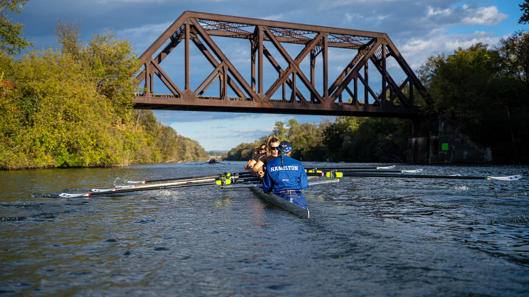 A boat passes under a bridge during women's rowing practice on the Erie Canal in fall 2026