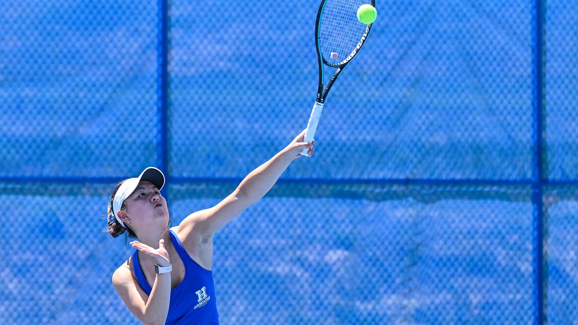 Muhan Cui serves a tennis ball during warm-ups before the Wesleyan match