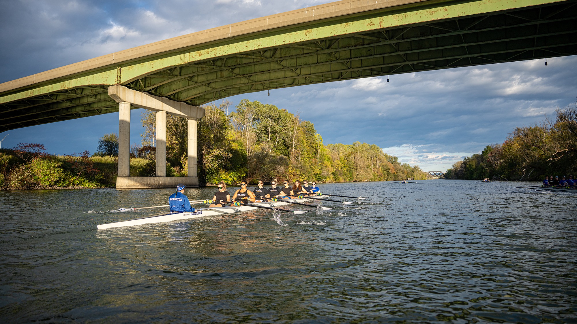 A boat passes under a bridge during women's rowing practice on the Erie Canal in fall 2026