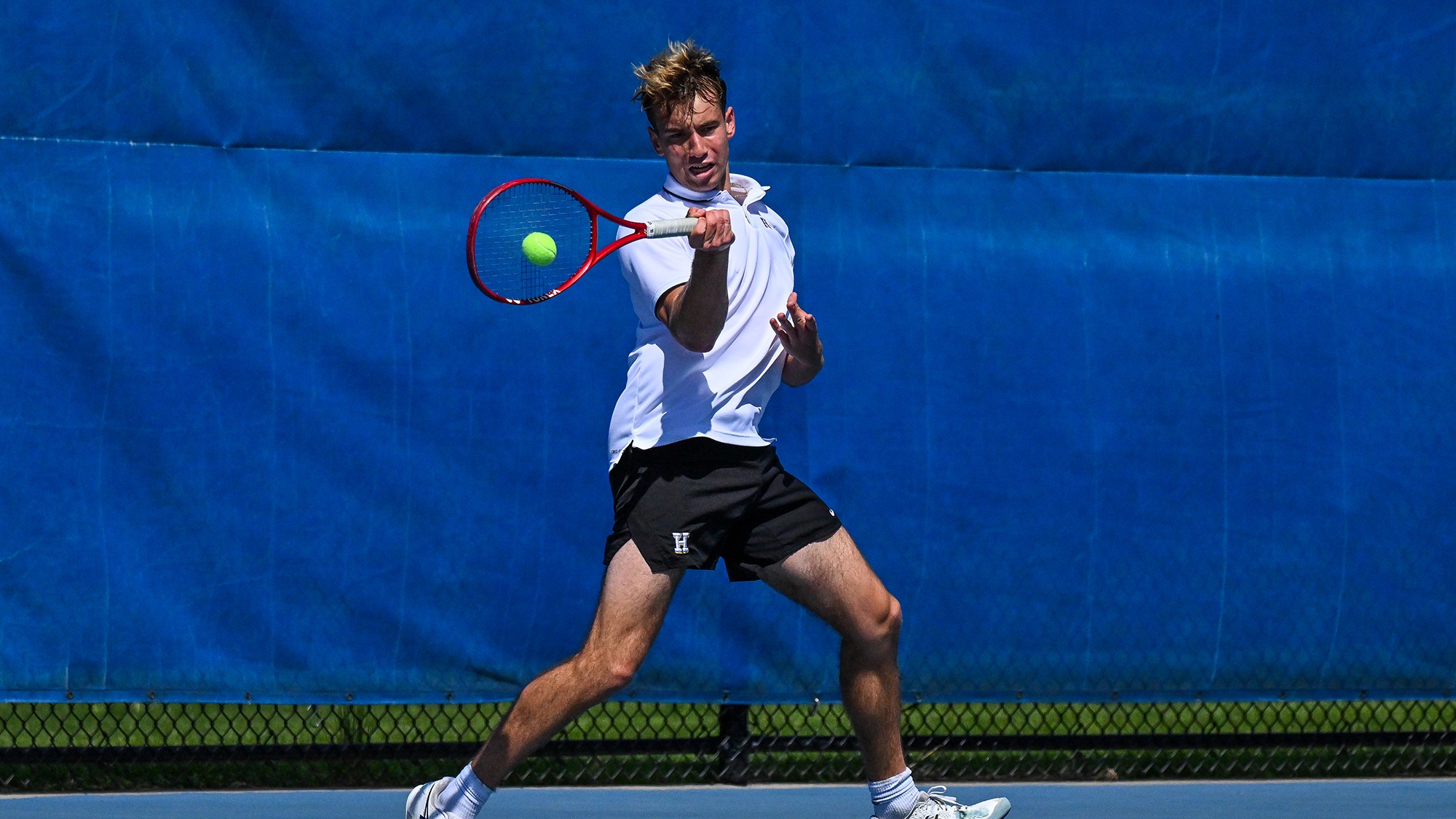 Alexei Katelevsky hits a forehand return during his men's tennis singles match against Wesleyan