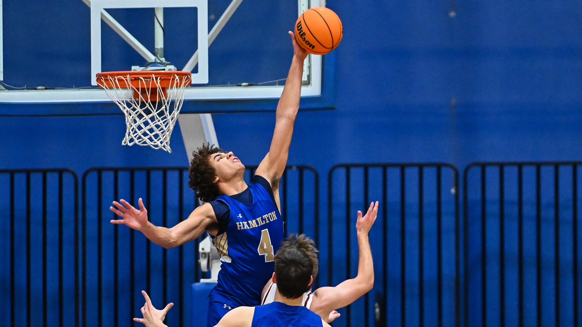Jalen Reese goes above the rim to block a shot in a men's basketball win against Bates