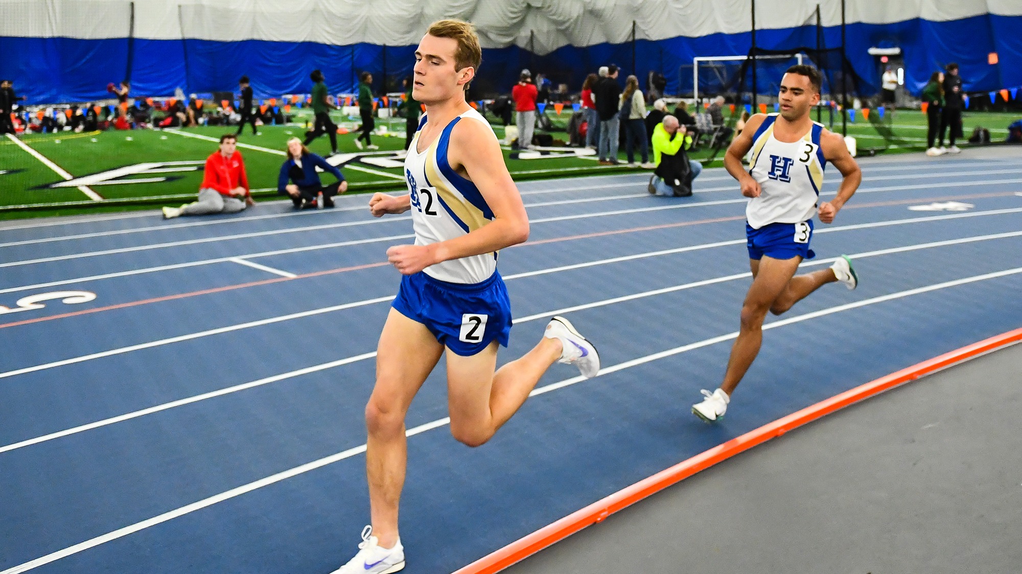 Henry Ebben runs ahead of Jeremy Bywater in the indoor 5000 meters at Utica University