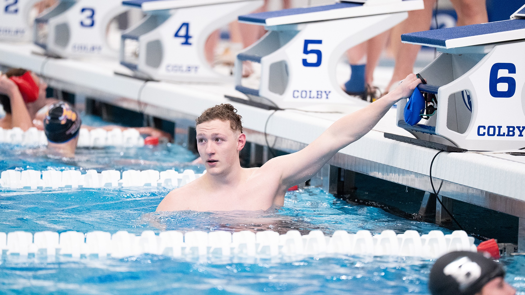 Nathaniel Taft holds onto the starting block and looks at his time after a race at the NESCAC Championships