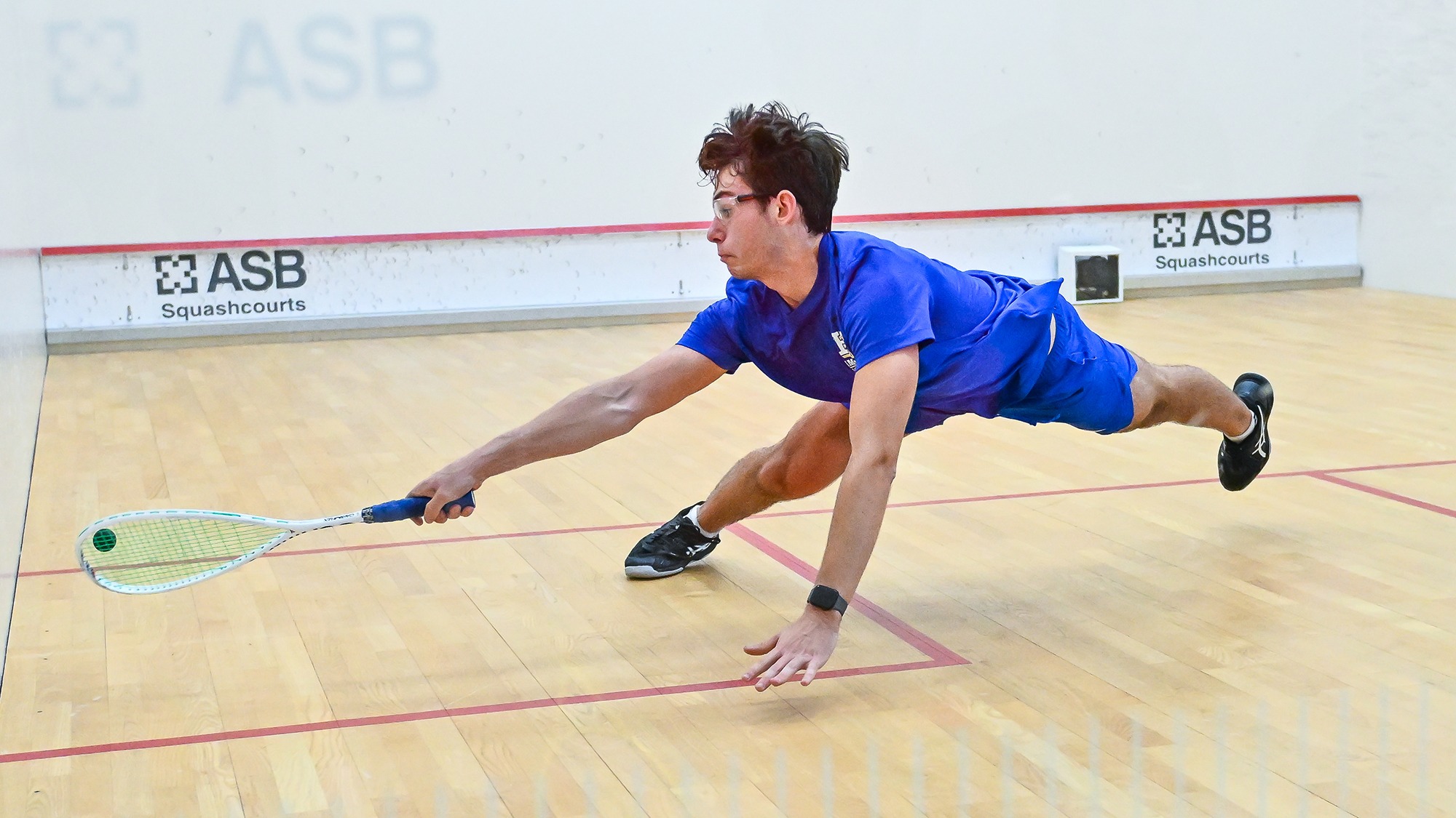 William Gianopulos dives to his left and hits the squash ball in his match against Denison