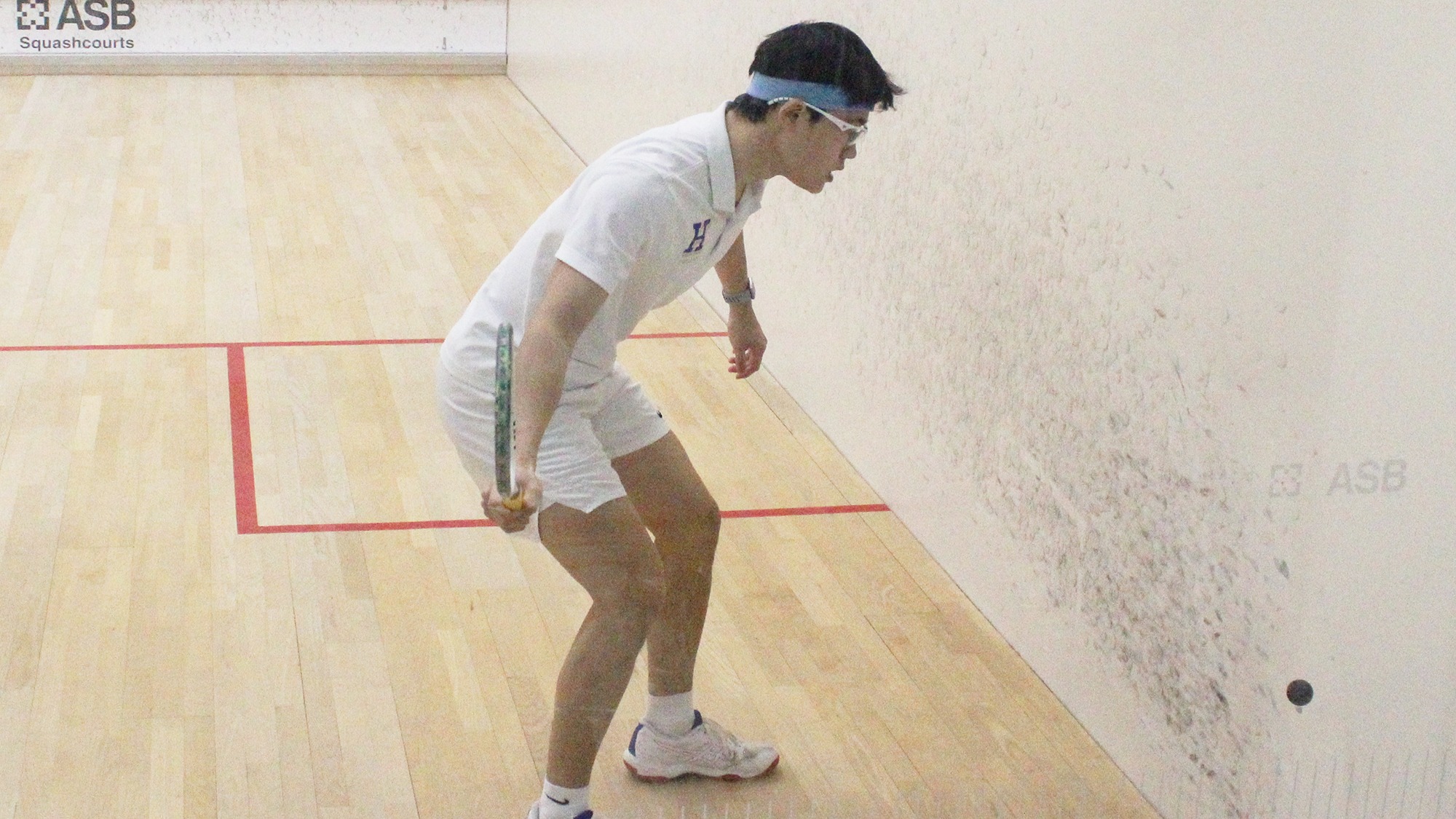 Jacob Li hits a forehand return near the wall in his NESCAC quarterfinal squash match against Trinity