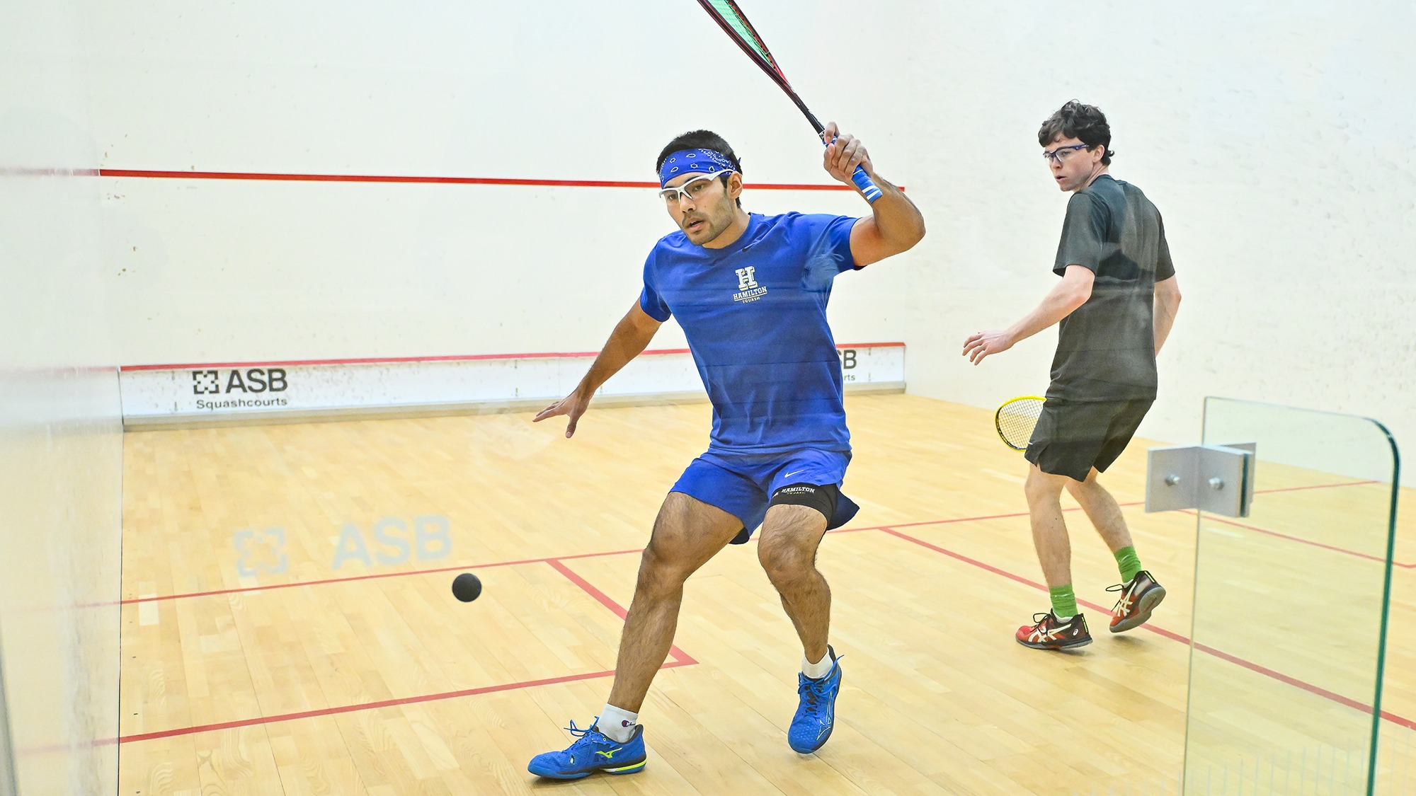 Atreyus Bhavsar prepares to hit a forehand return in his men's squash match with Denison
