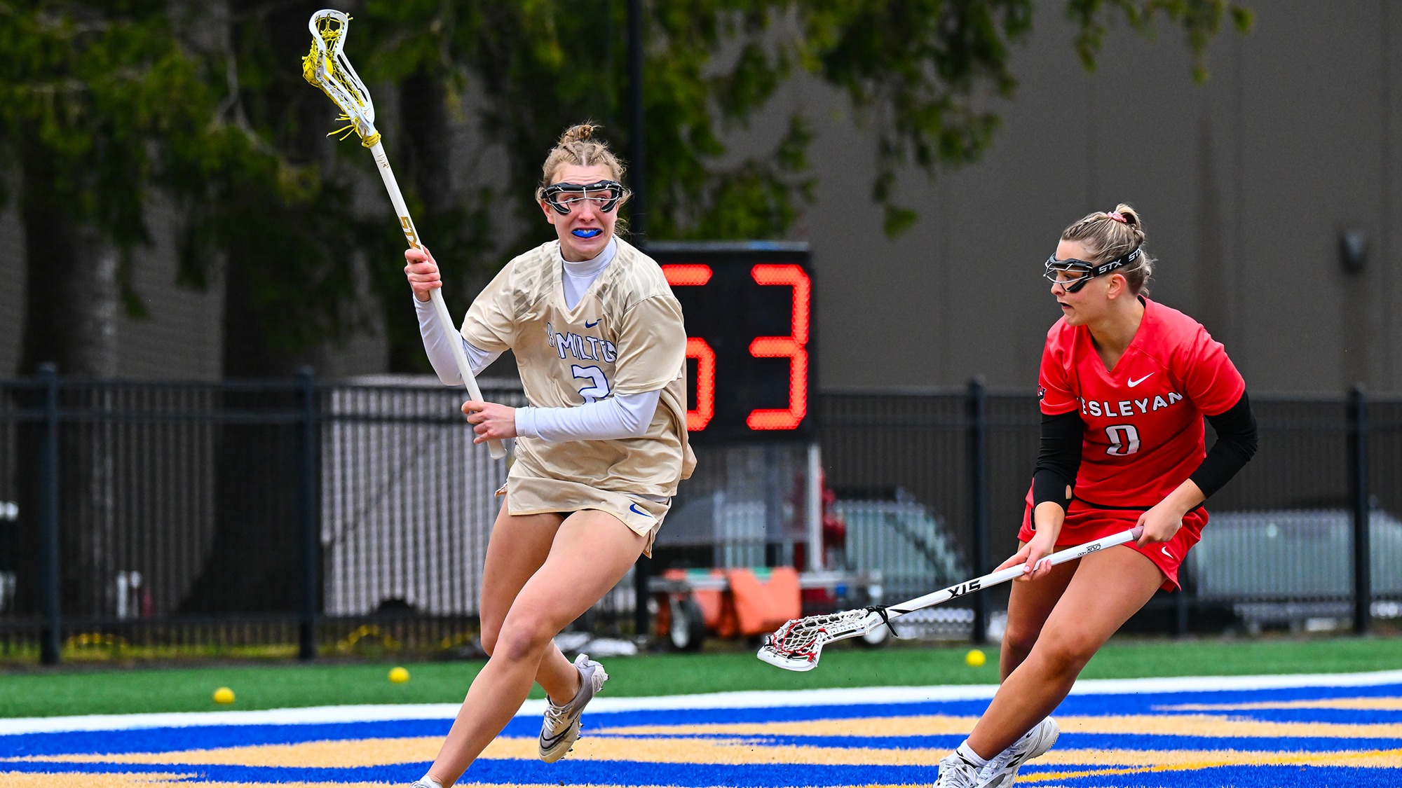 Lily Goldsmith runs behind Wesleyan's goal and looks for a women's lacrosse teammate to pass to