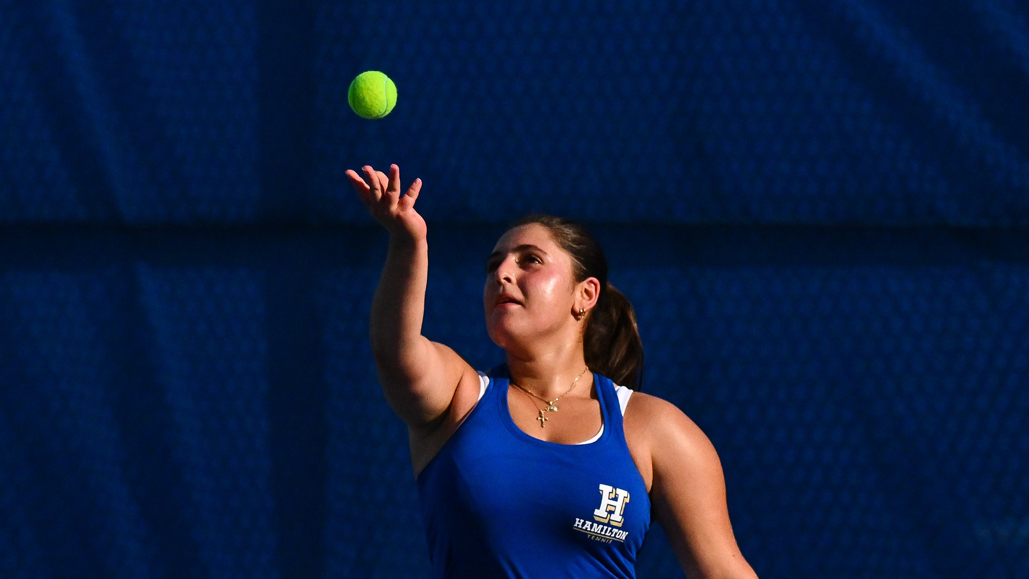 Mona Farah tosses the tennis ball in the air to serve it during a September 2025 practice
