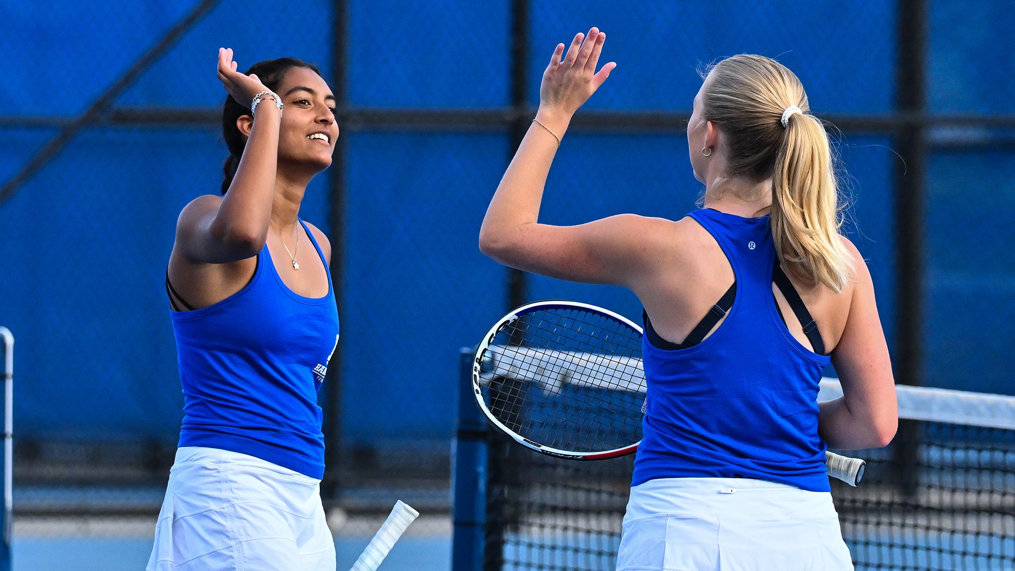 Priyanka Challapalli high-fives a doubles teammate during women's tennis practice in September 2025