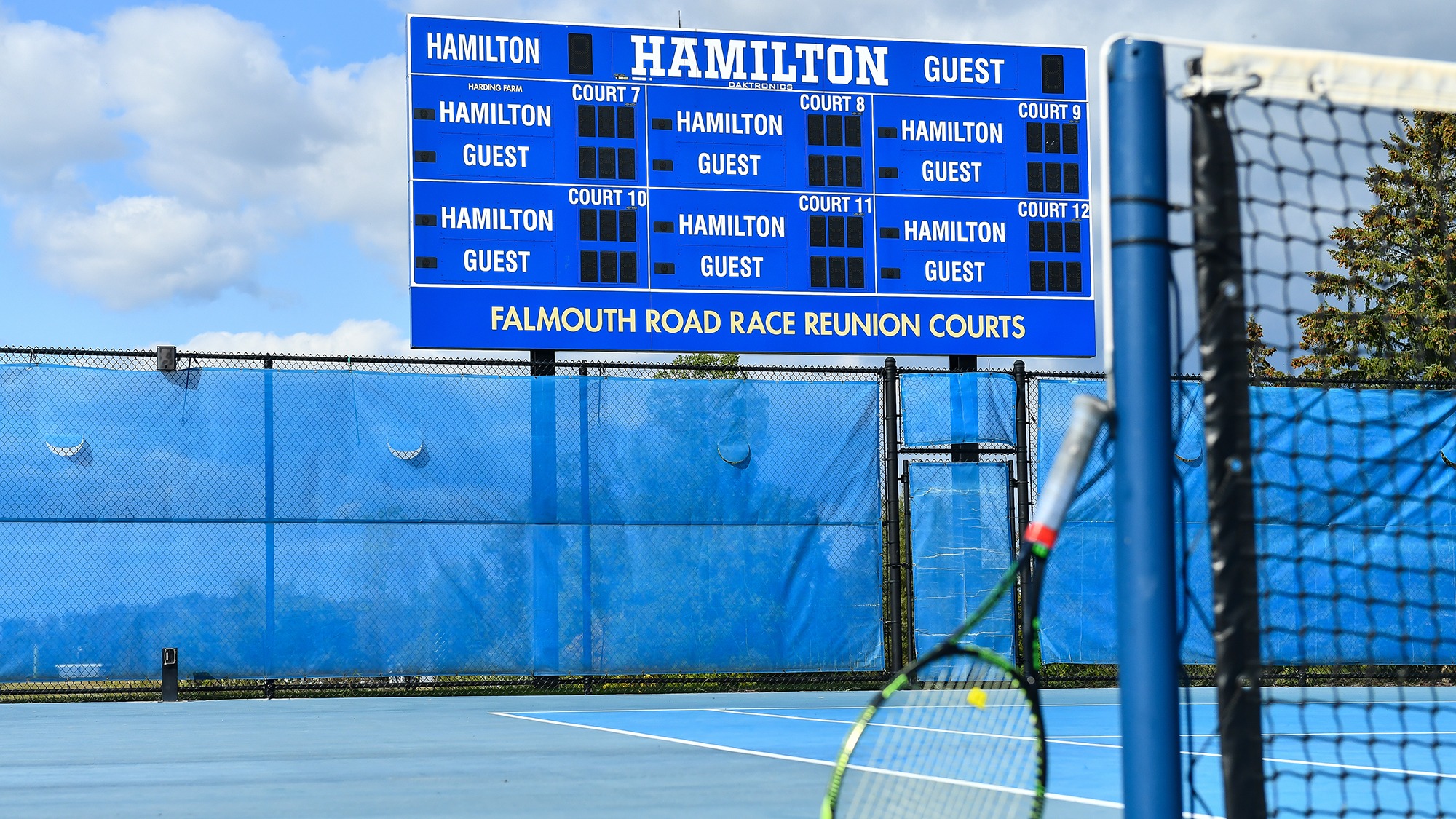 The Tiejte Family Tennis Center scoreboard with a racket in the foreground