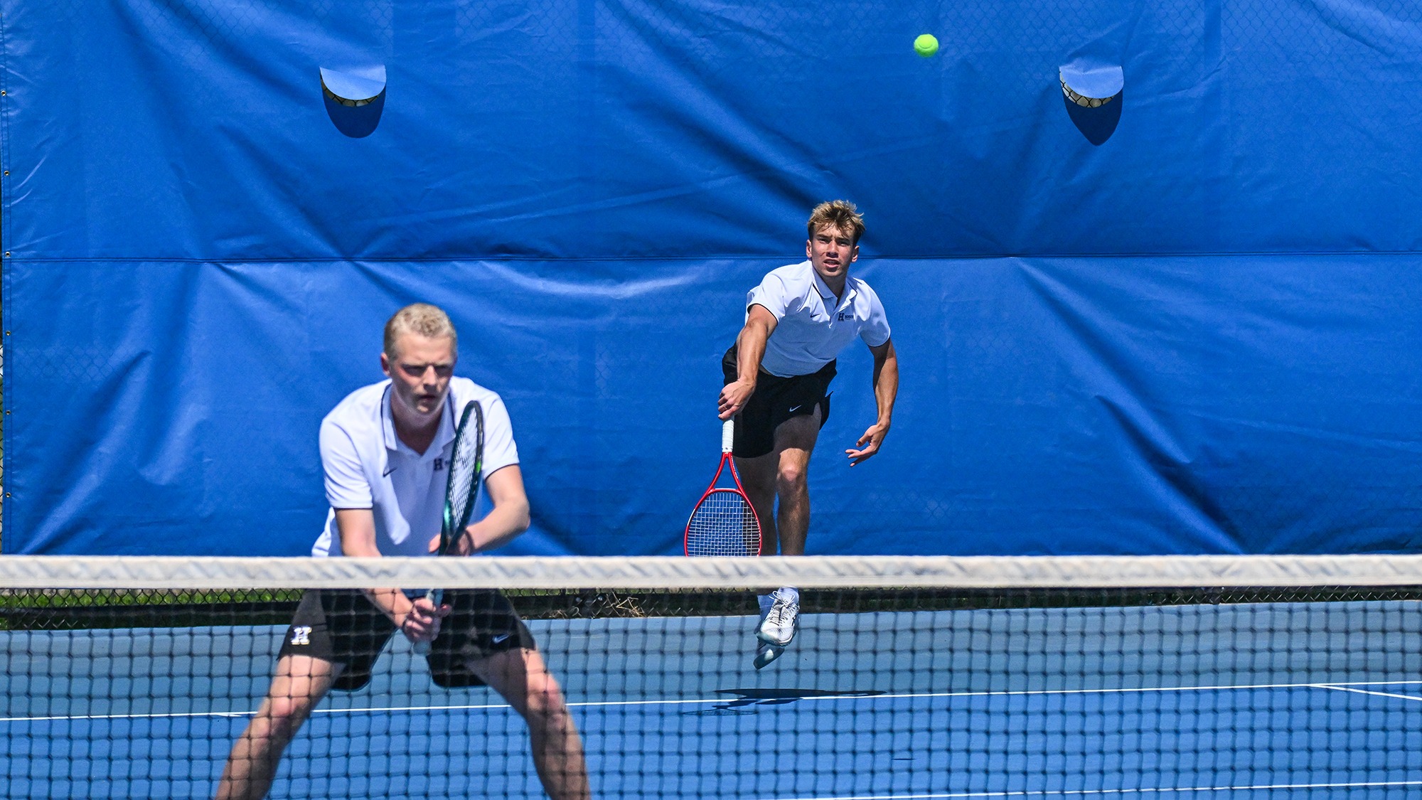 Alexei Katelevsky serves while Filip Moller stands at the net during their 2026 men's tennis doubles match with Wesleyan