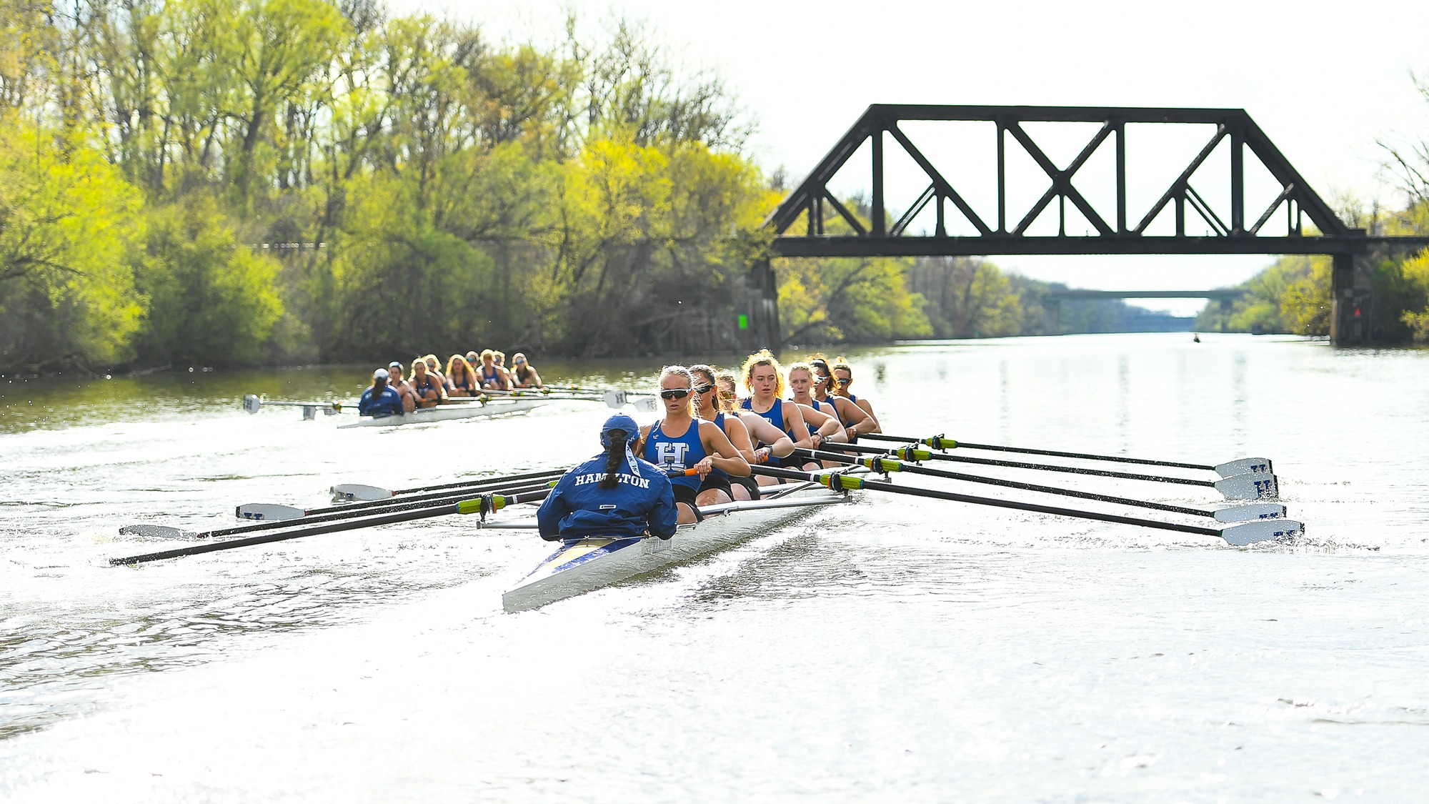Two boats race on the Erie Canal during women's rowing practice in April 2026