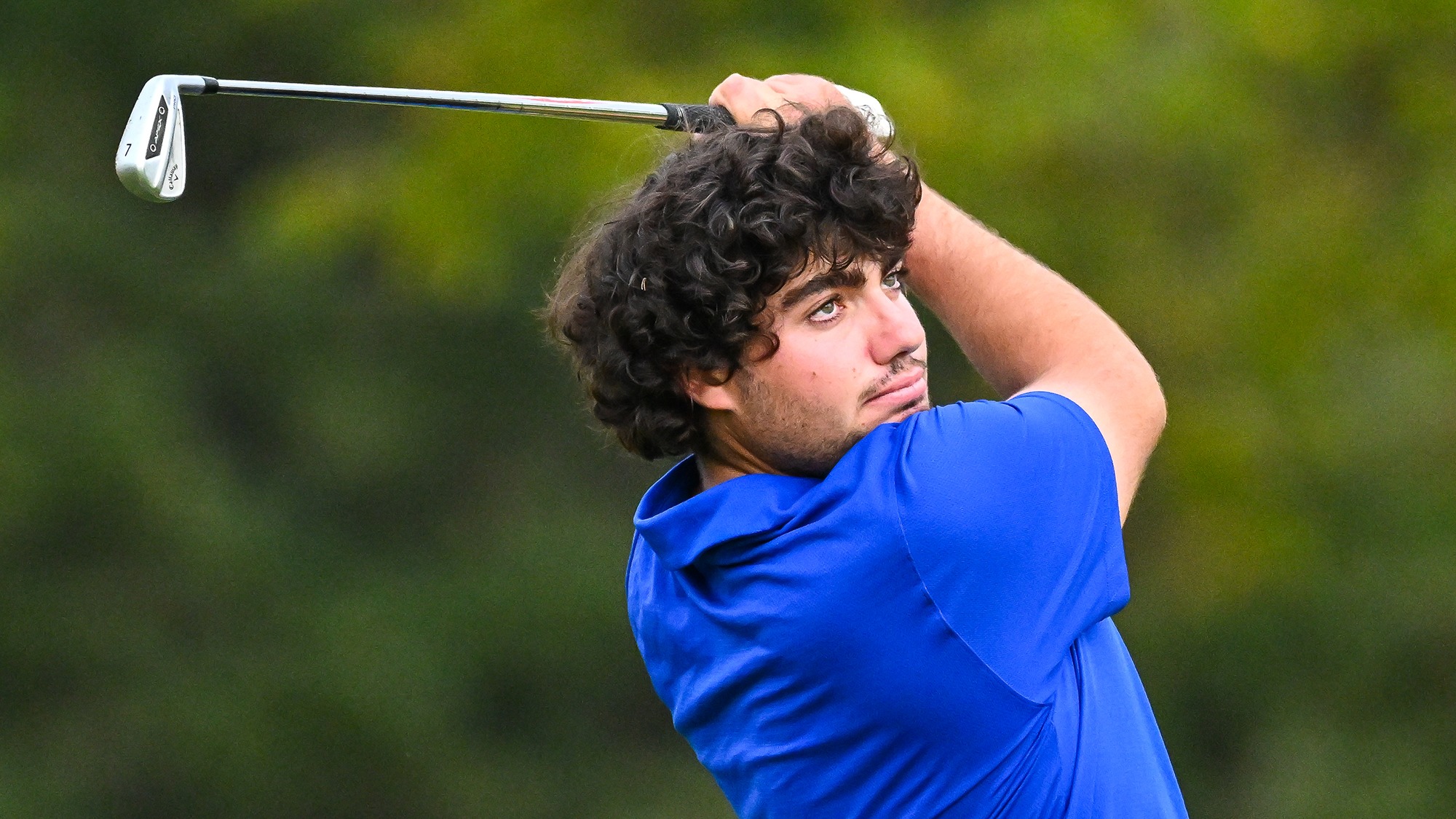 Ramon Aroca Gonzalez watches his 7-iron shot on the driving range during men's golf practice