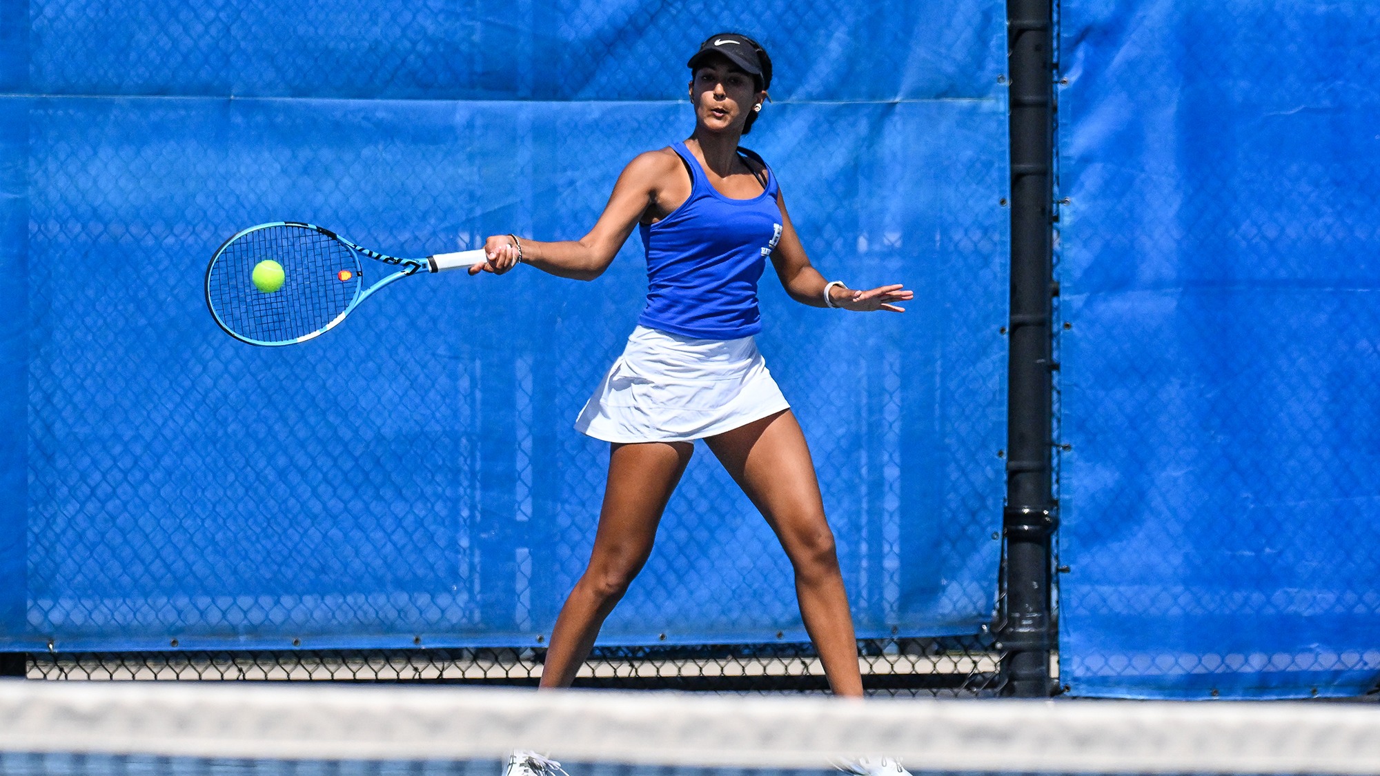 Priyanka Challapalli hits a forehand return in a women's tennis match against Wesleyan