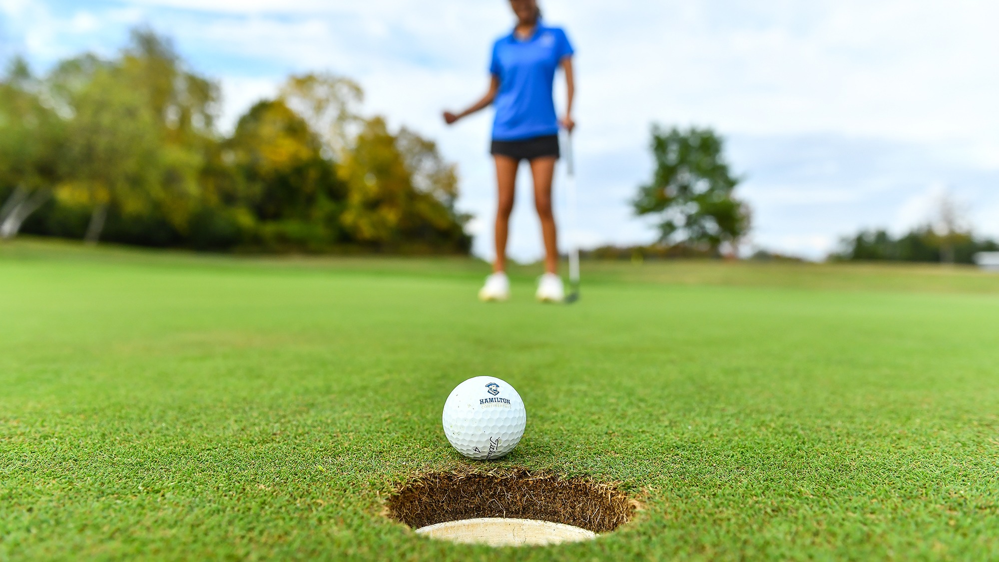 A golf ball rolls into the hole on the putting green at the Bob Simon Golf Facility