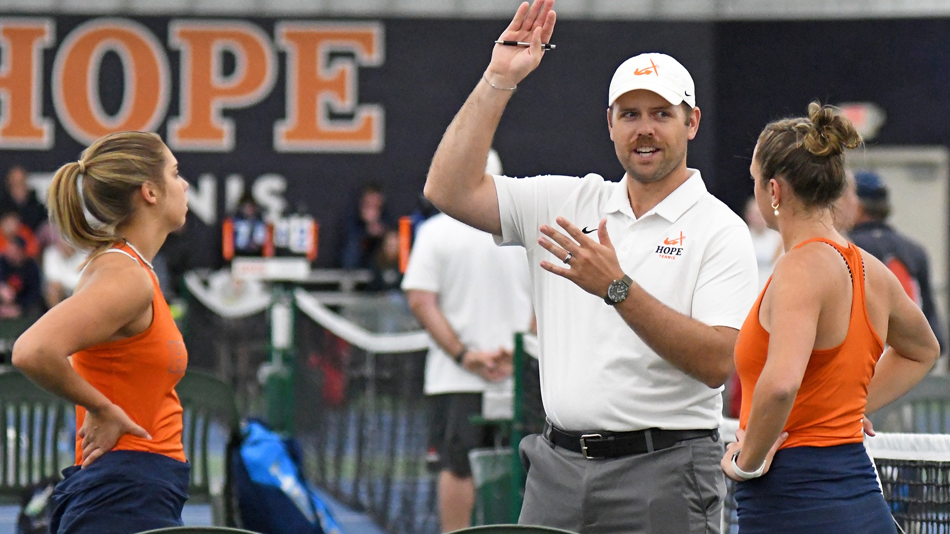 Austin Hunt discussing a play with two women tennis players