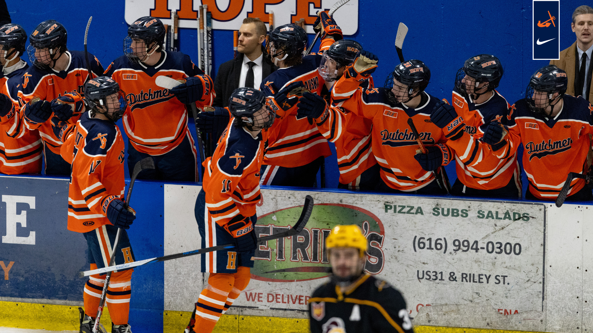 The Hope College men's hockey team celebrates on the bench after scoring vs. Calvin.