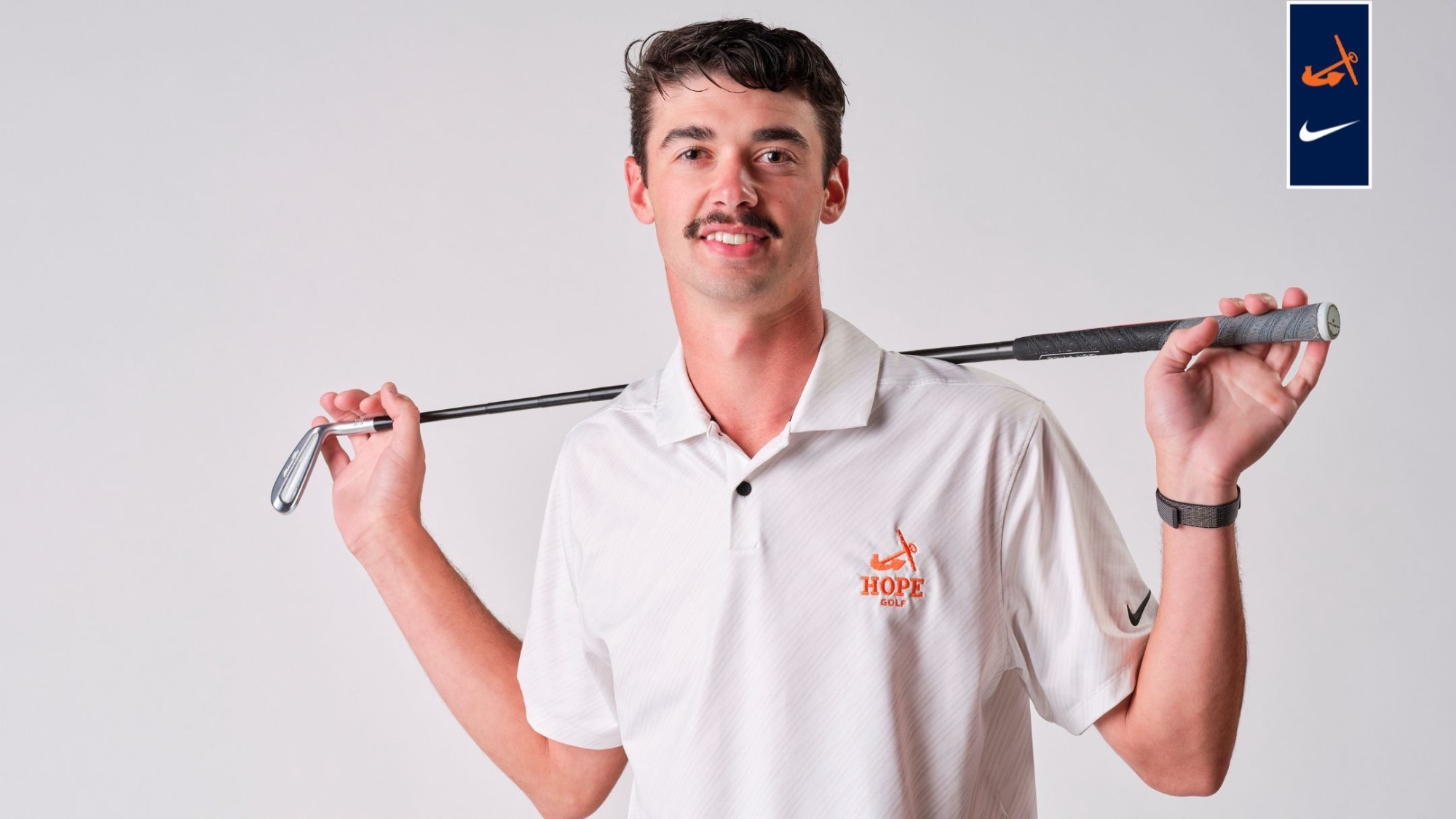 Eli Voisard holds a golf club on his shoulders.