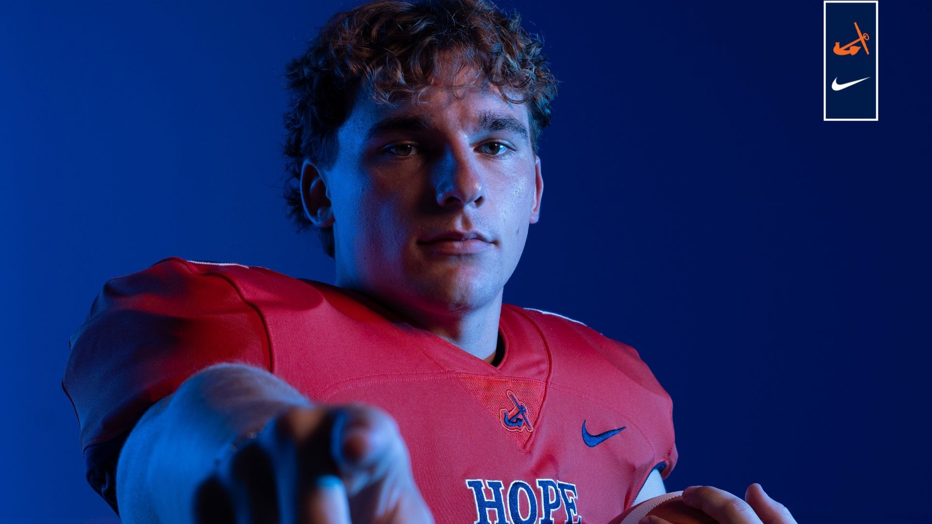 Trevor Griffiths holds a football and points toward the camera.