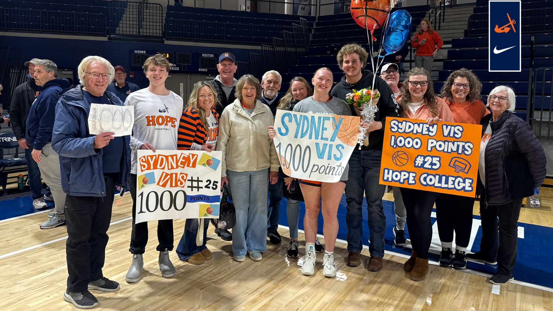 Sydney Vis poses for a post-game picture with her family and signs honoring her 1,000-point meilstone.