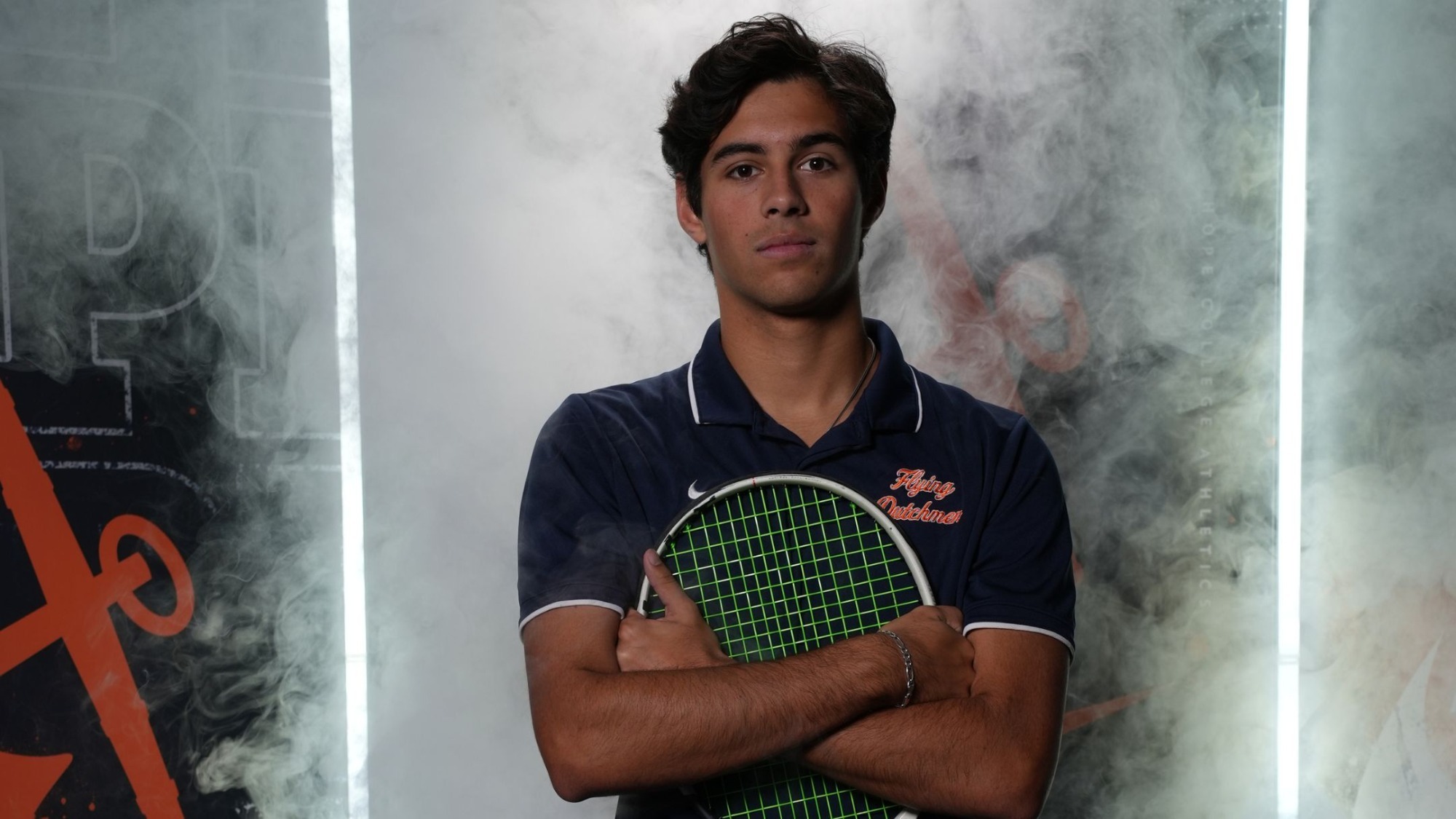 Karsten Patel holds a tennis racket on his chest.