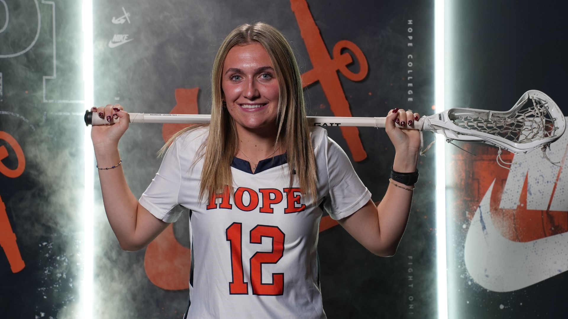 Stella Bottum holds a lacrosse stick on her shoulders.