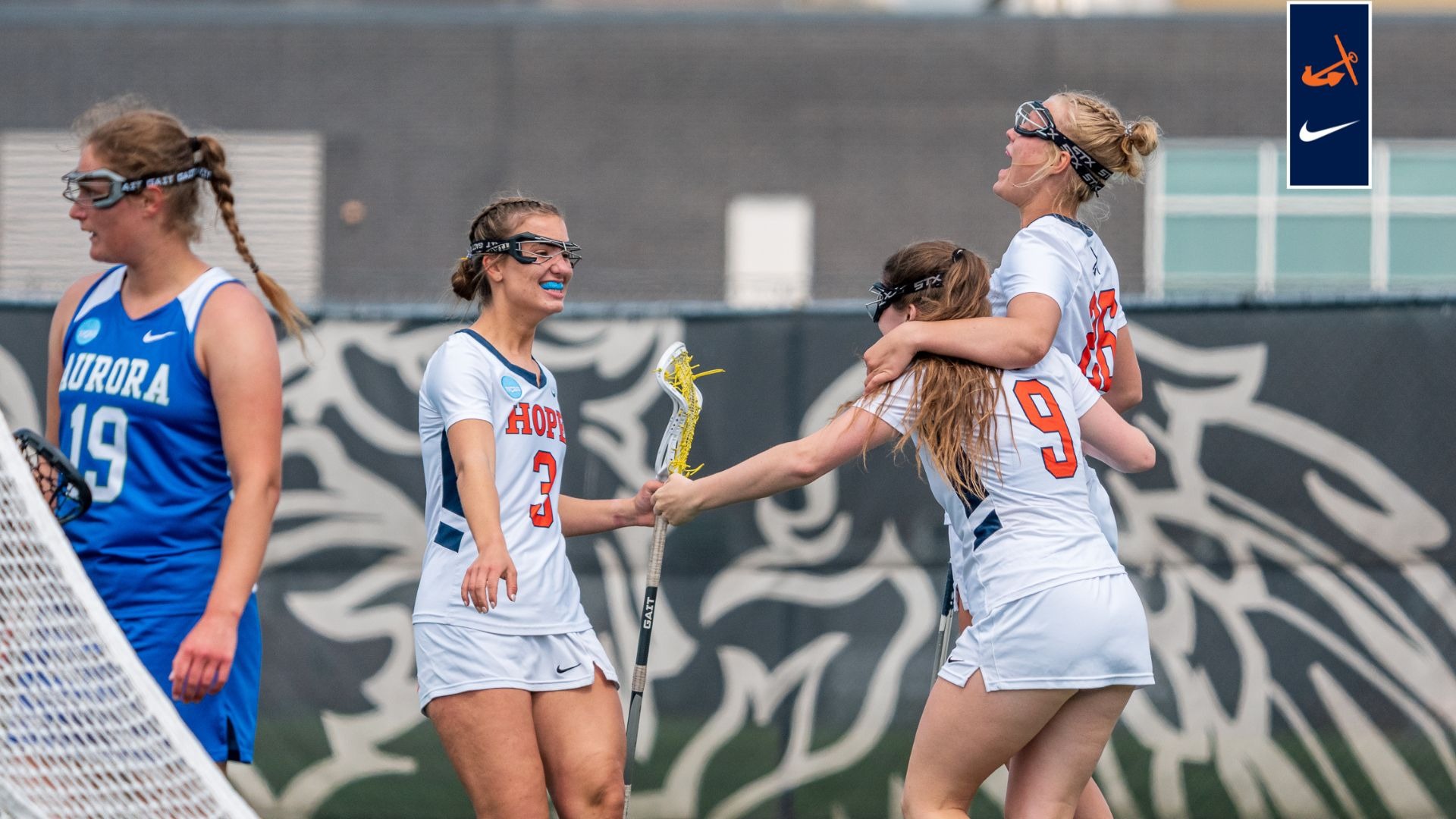 Three Hope women's lacrosse teammates celebrate after a goal.