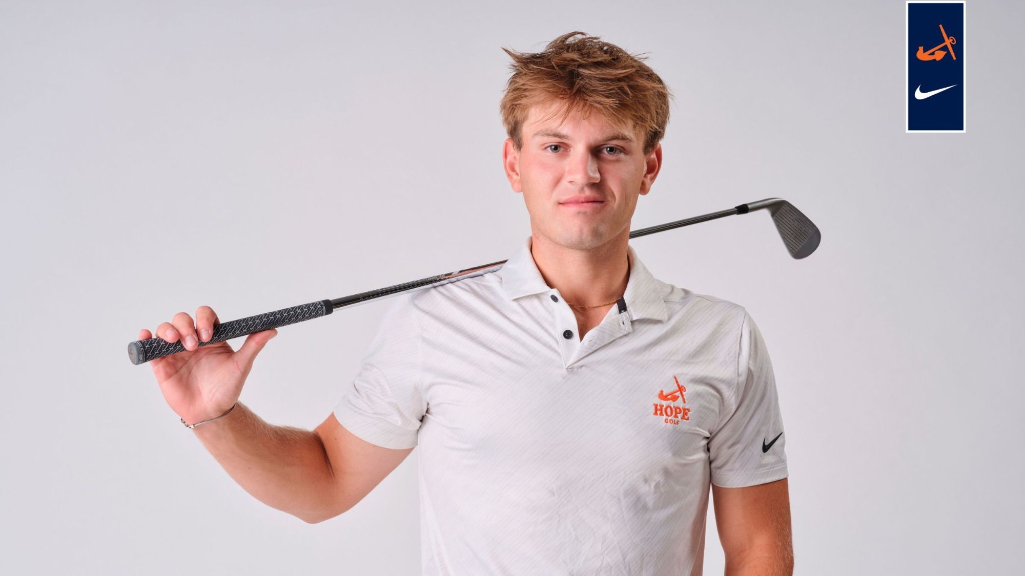 Golfer Max Shulman holds a wedge on his right shoulder.