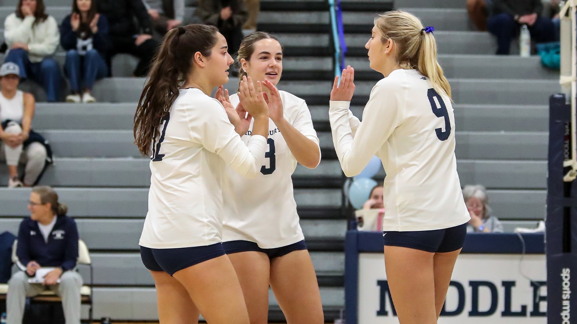 A huddle between Middlebury volleyball athletes Sophie Horn, Campbell Bartley and Sophie Fisher against Amherst last fall.