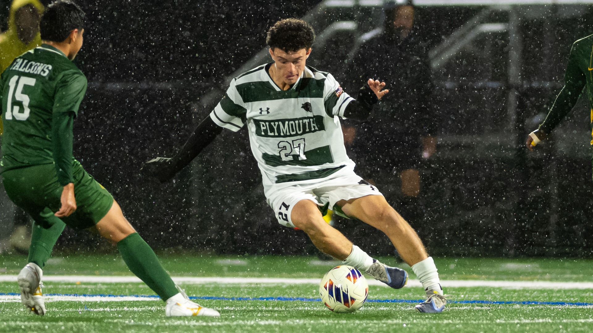 Michael Mezzetti cuts around a Fitchburg State defender in the pouring rain