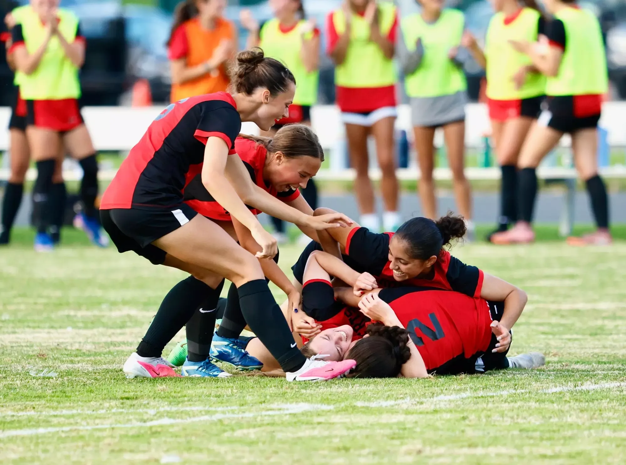 Roberts Wesleyan University women's soccer players jump on top of Sam Cipolla after Cipolla scored her second goal late in a game against Thomas More University.
