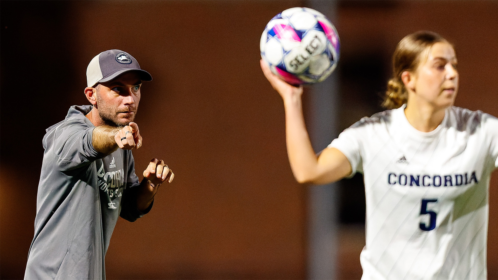 Women's soccer coach Nick Smith giving instructions from the sideline.