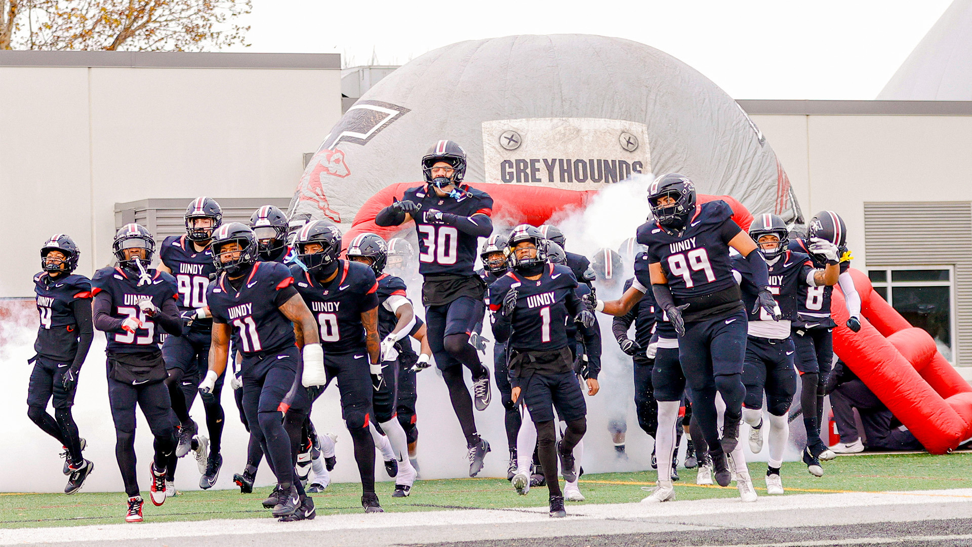 Members of the UIndy football team take the field before a home game.
