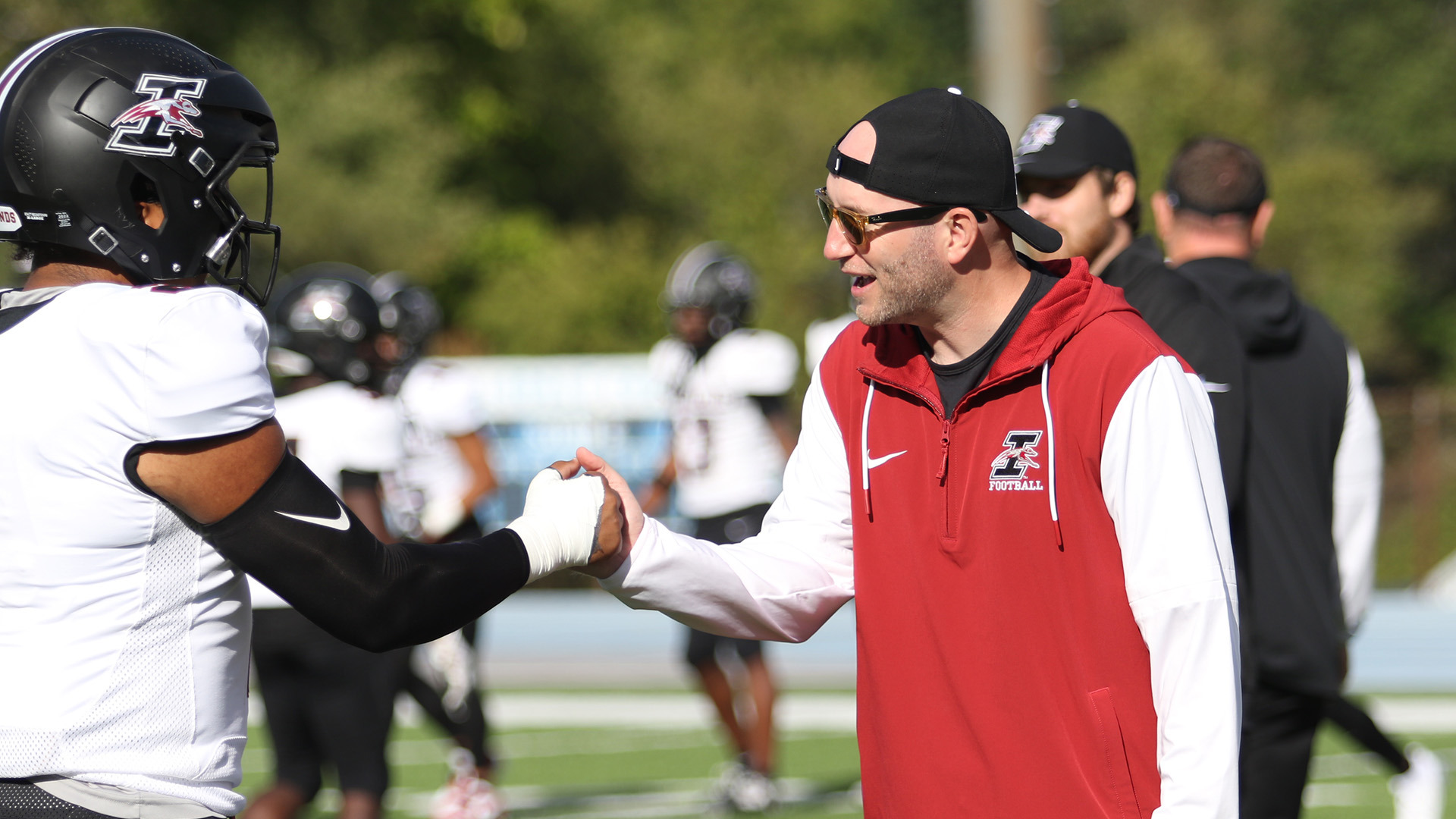 UIndy football coach Michael Engle interacting with a player.