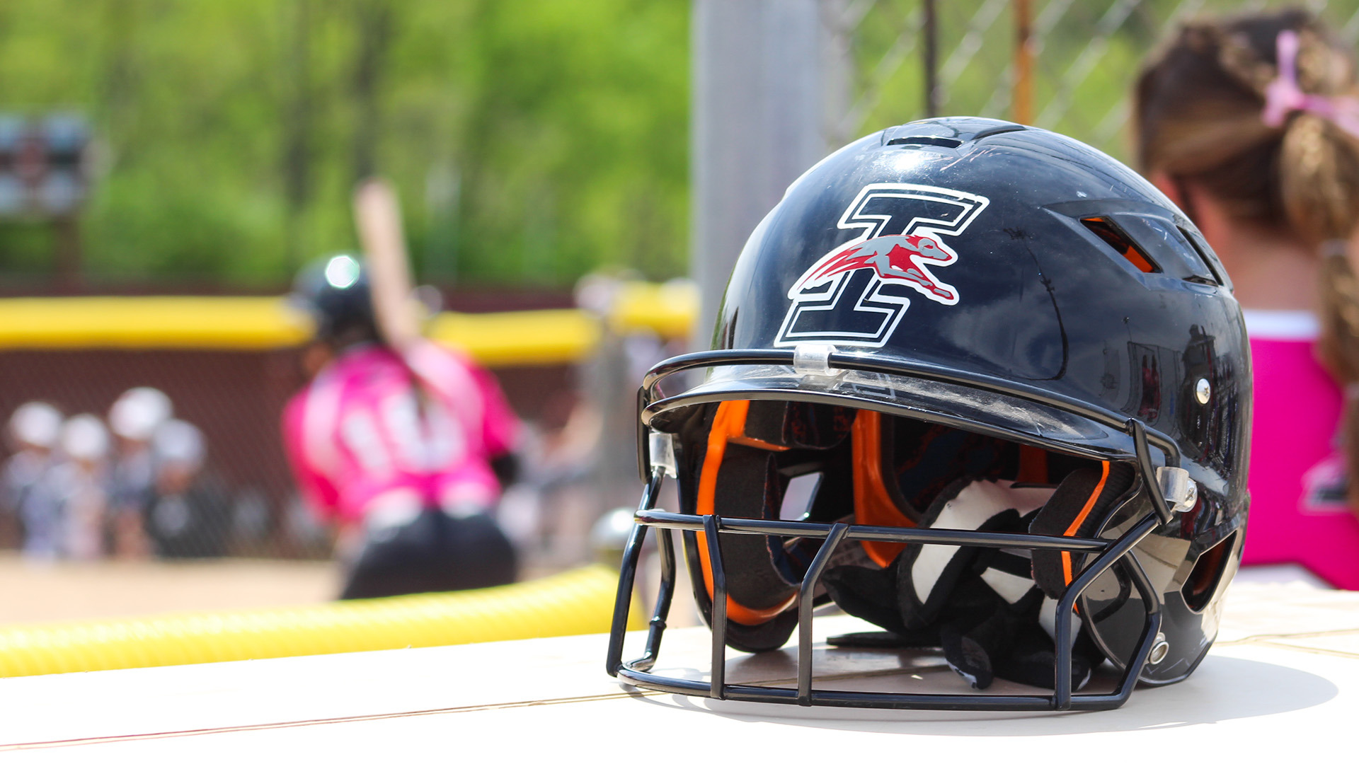 A UIndy softball helmet sitting on top of the dugout.
