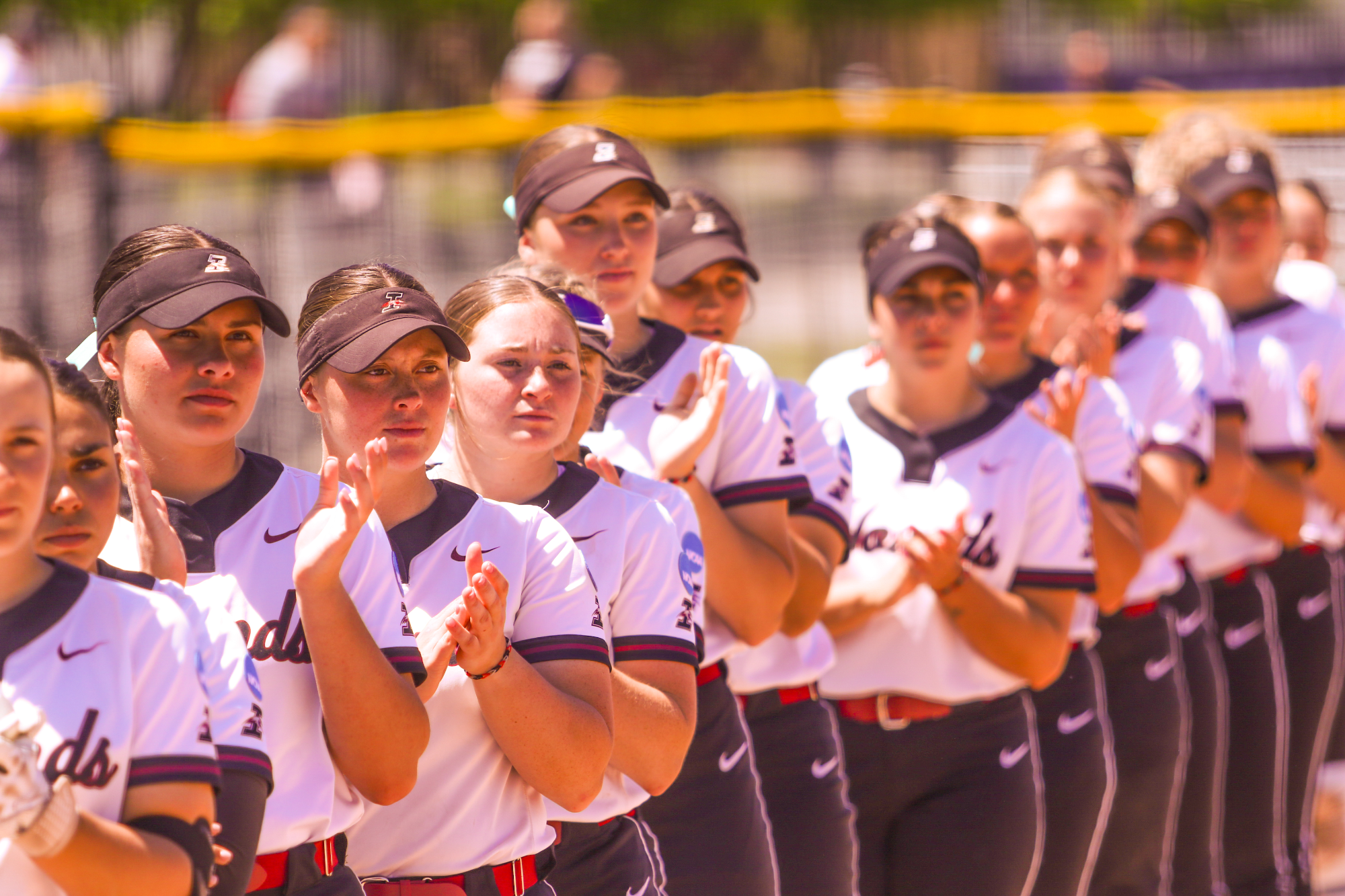 The UIndy softball team lined up on the third base line, clapping as the opponent's starting lineup is announced.