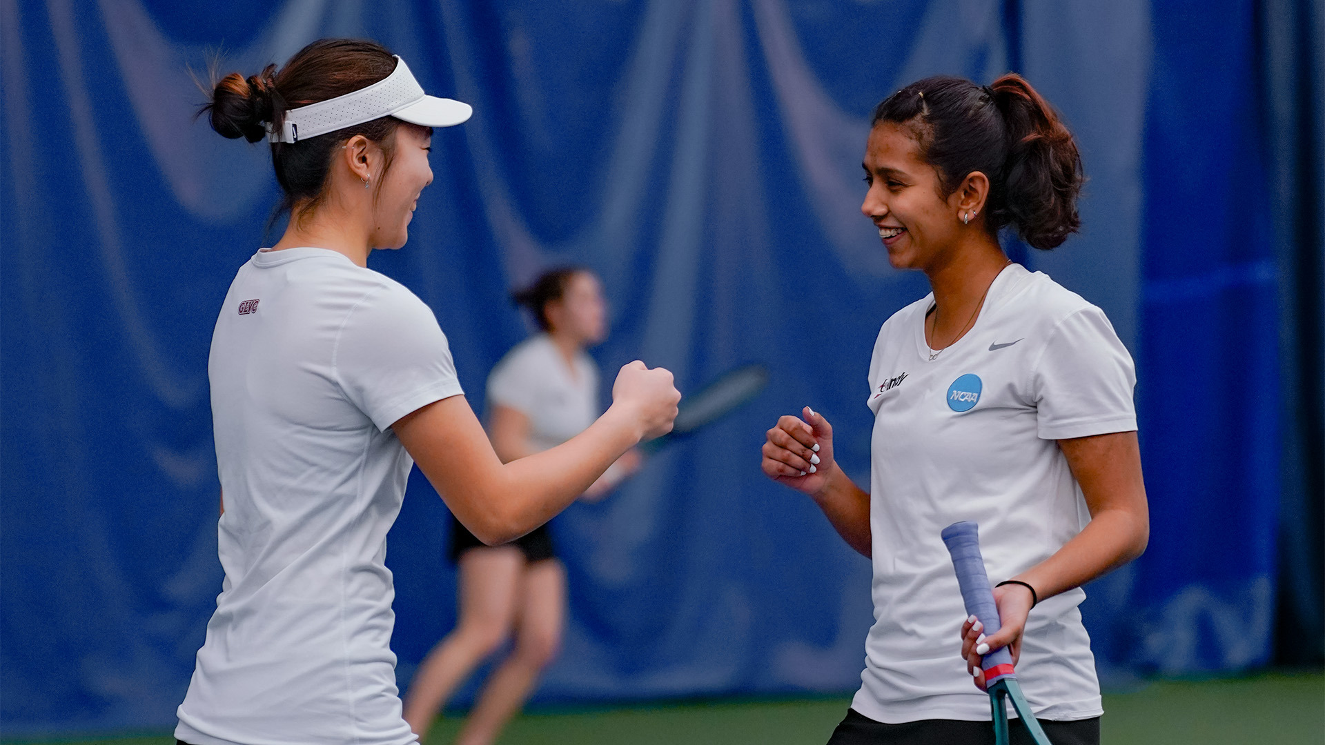 UIndy tennis student-athletes abd doubles partners Suryanshi and Linya Chen fist bump.
