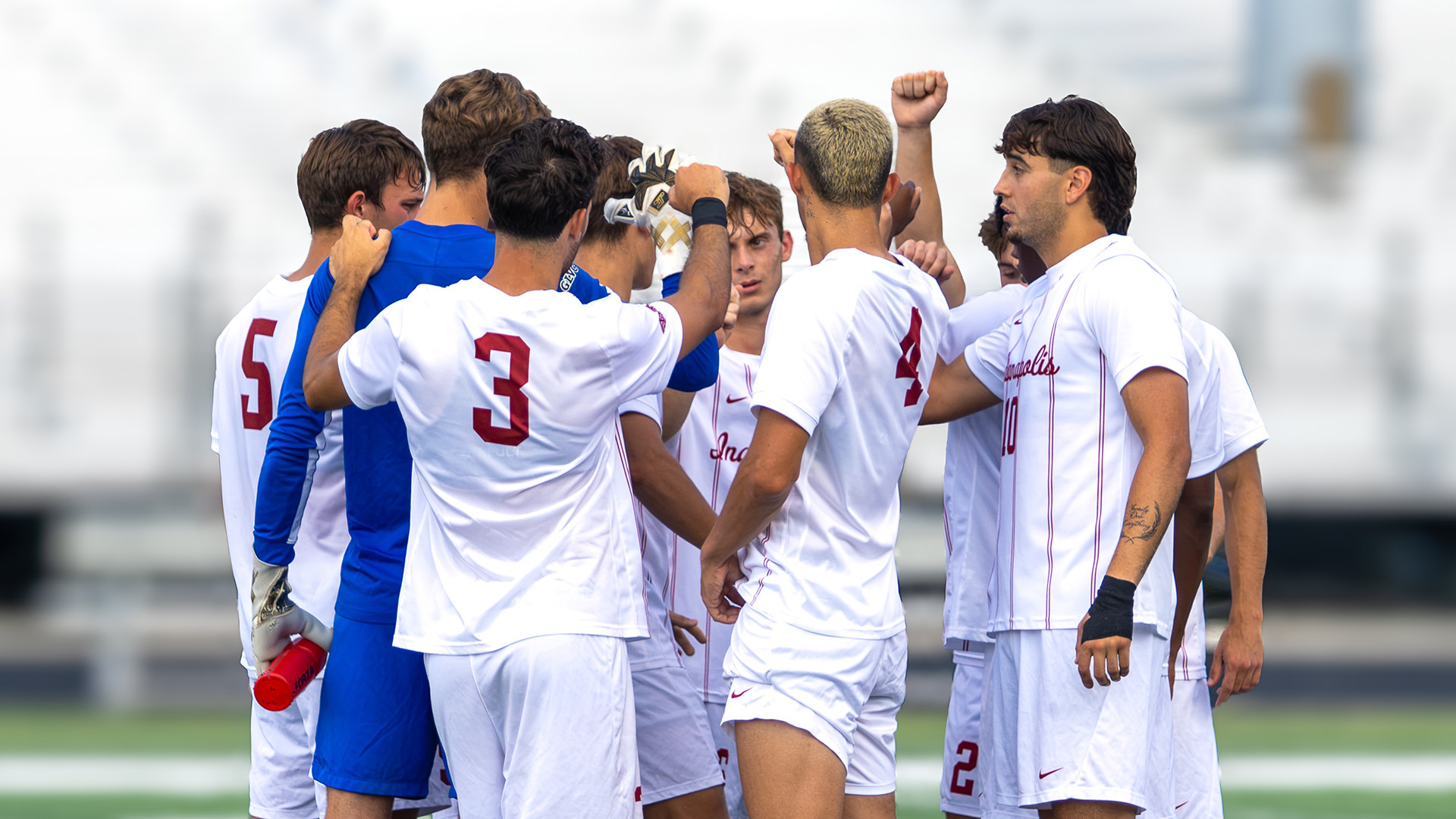 The UIndy men's soccer team huddling on the field.