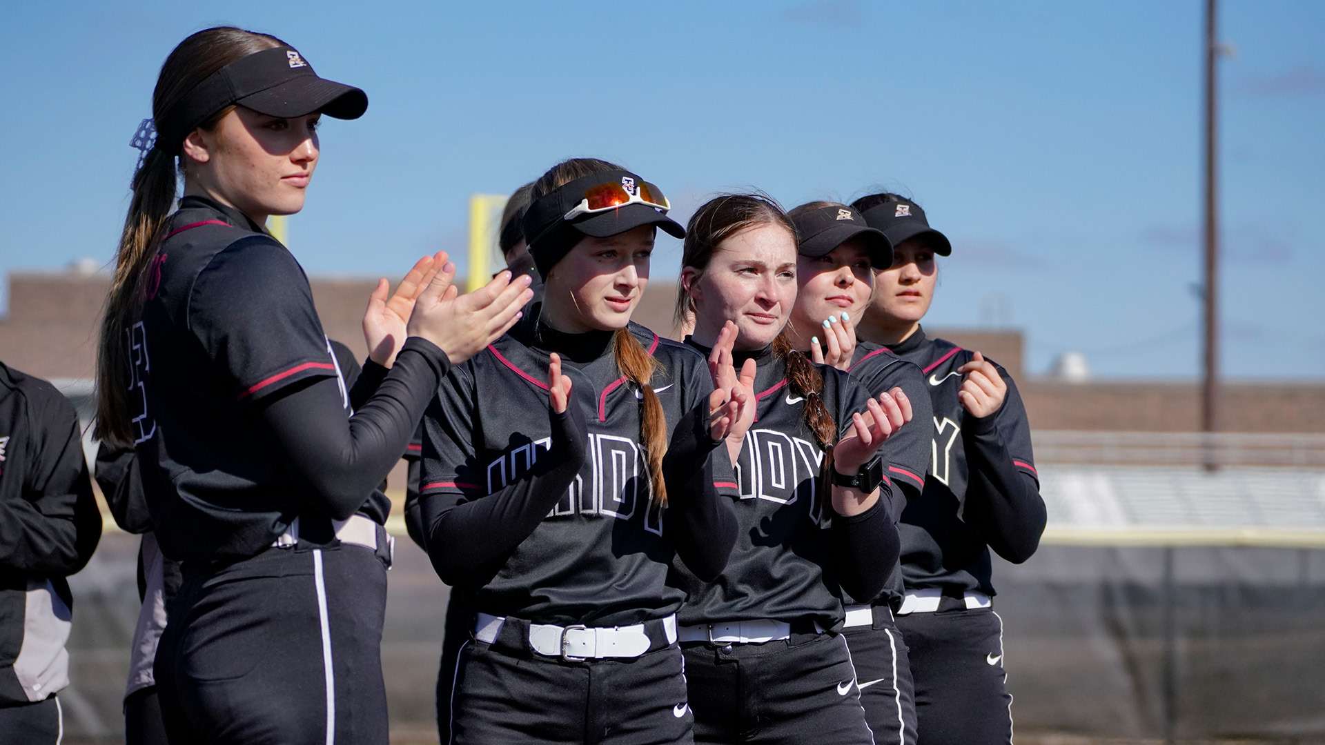 Members of hte UIndy softball team clapping.
