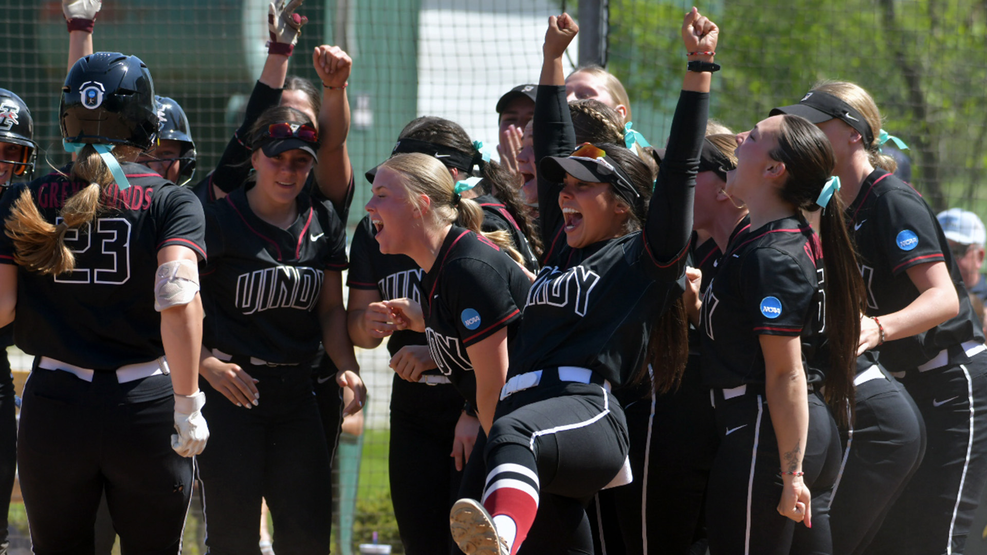 The UIndy softball team gathers at home plate to celebrate a home run.