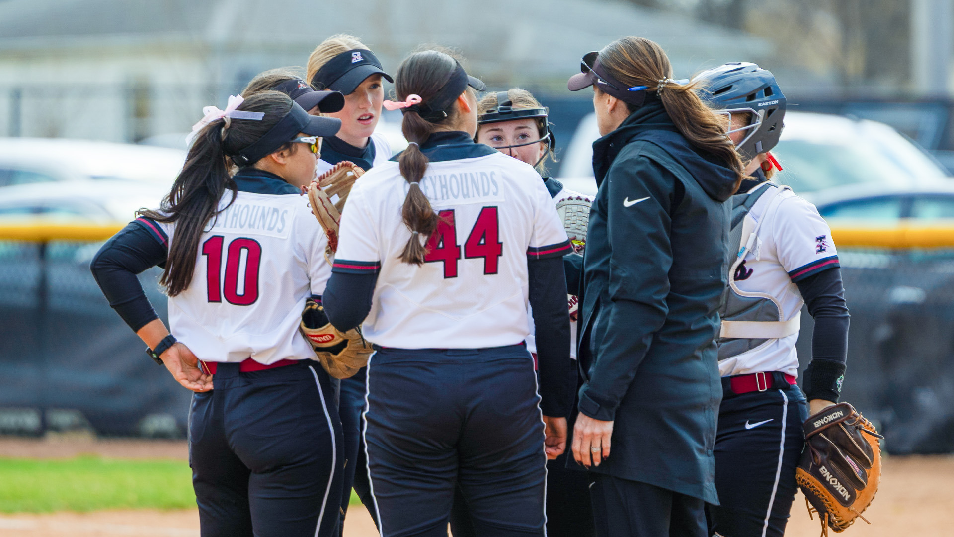 The UIndy softball infield hiddling with Coach Frost in the circle.